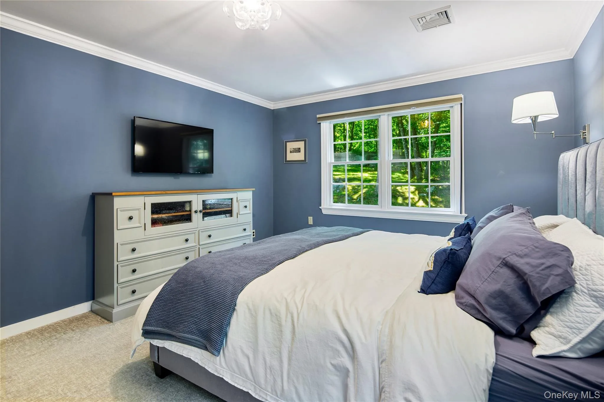 Primary bedroom is king size with bedside wall mounted Hanson lamps, crown molding, wall-to-wall carpeting, en-suite primary bath, and walk-in closet Primary bedroom is king size with bedside wall mounted Hanson lamps, crown molding, wall-to-wall carpeting, en-suite primary bath, and walk-in closet