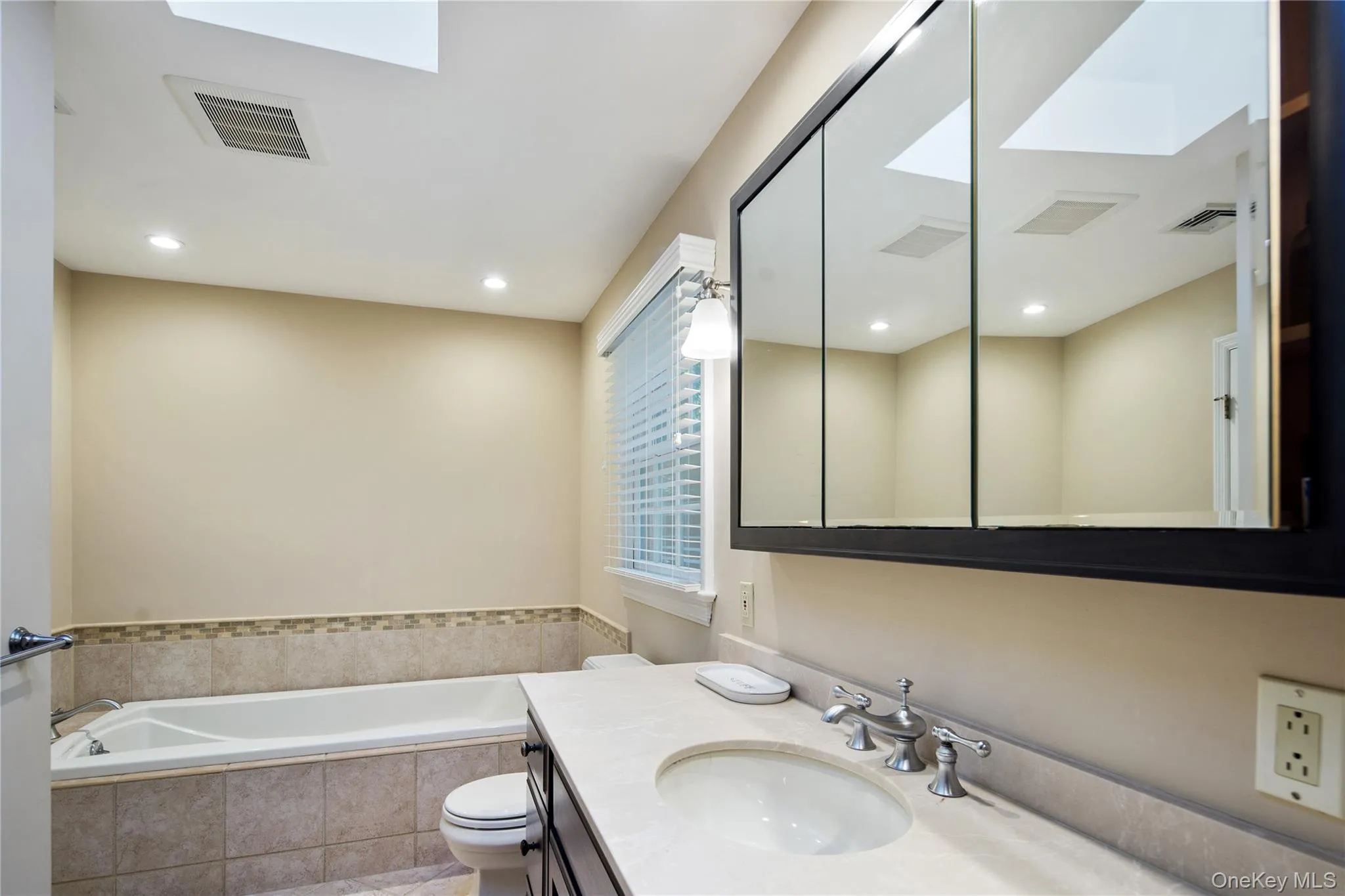 Recessed lighting, a skylight and an inset marble border Recessed lighting, a skylight and an inset marble border