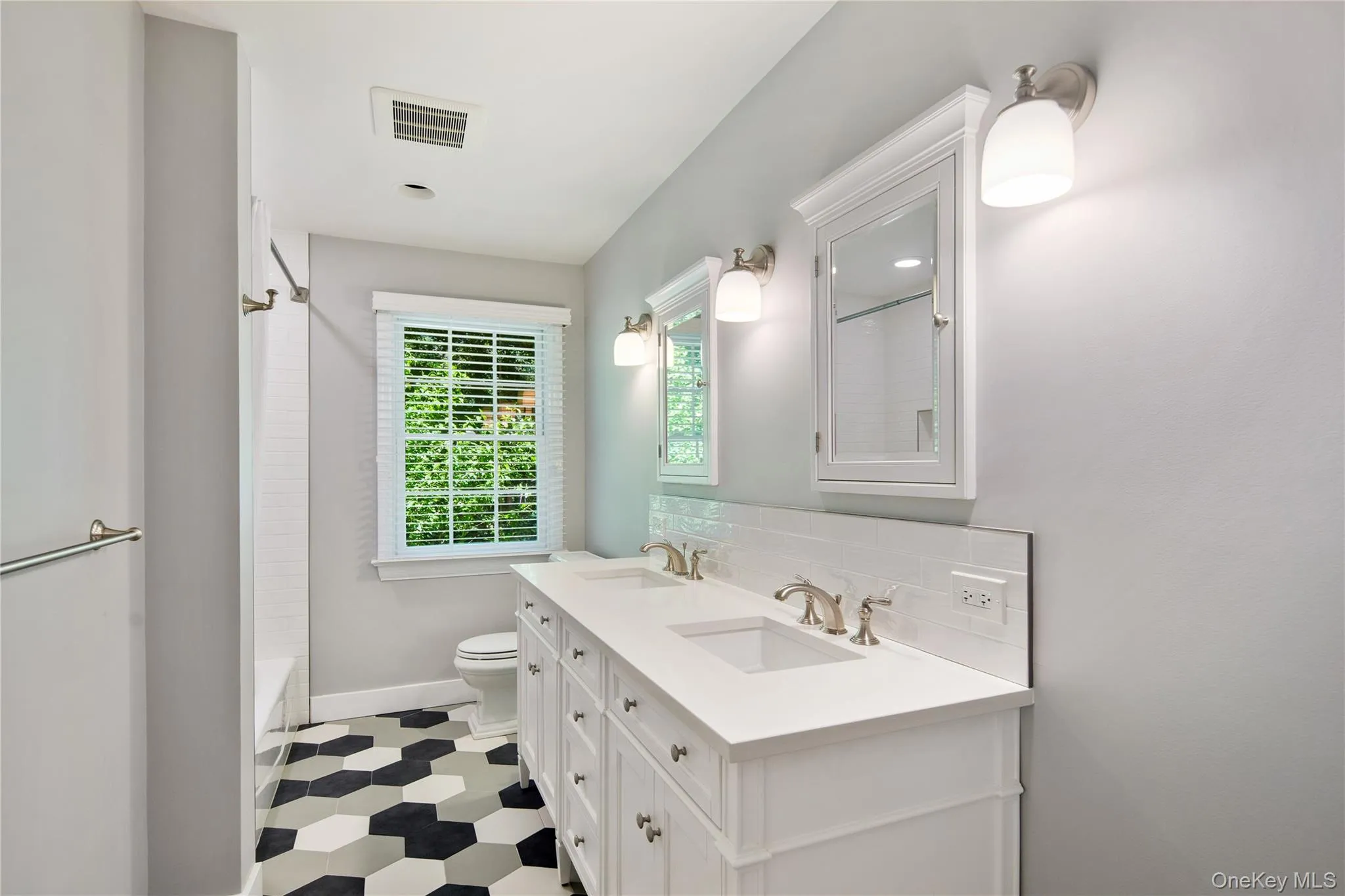 The new hall bath offers stylish multi-colored hexagon porcelain tile floor, subway tile surround, a full tub, storage vanity with two undermount sinks, inset medicine cabinets with beveled mirrors, and wall sconces. The new hall bath offers stylish multi-colored hexagon porcelain tile floor, subway tile surround, a full tub, storage vanity with two undermount sinks, inset medicine cabinets with beveled mirrors, and wall sconces.
