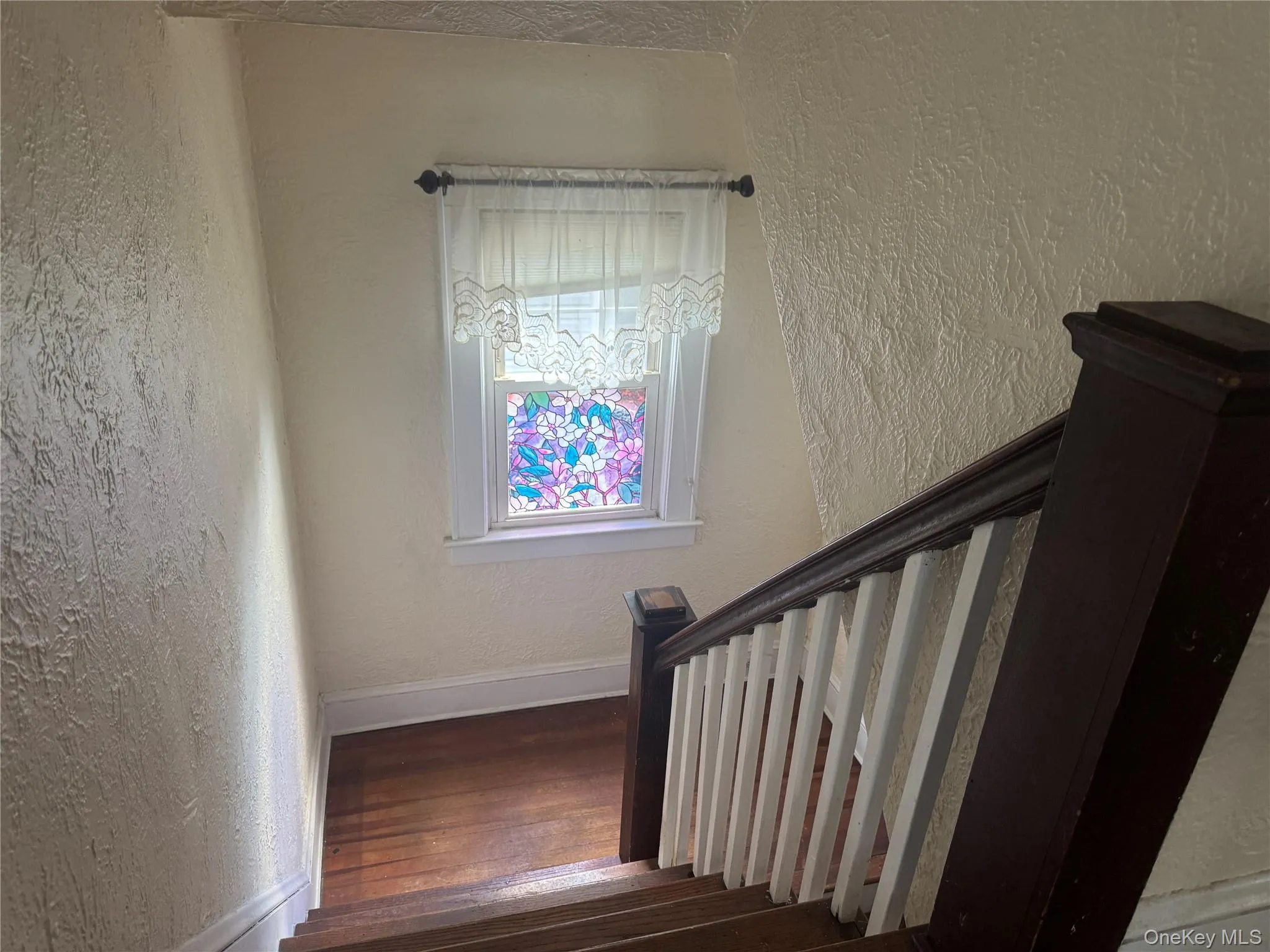 Staircase featuring wood-finish treads and risers, a dark wood-finish handrail, and white balusters Staircase featuring wood-finish treads and risers, a dark wood-finish handrail, and white balusters