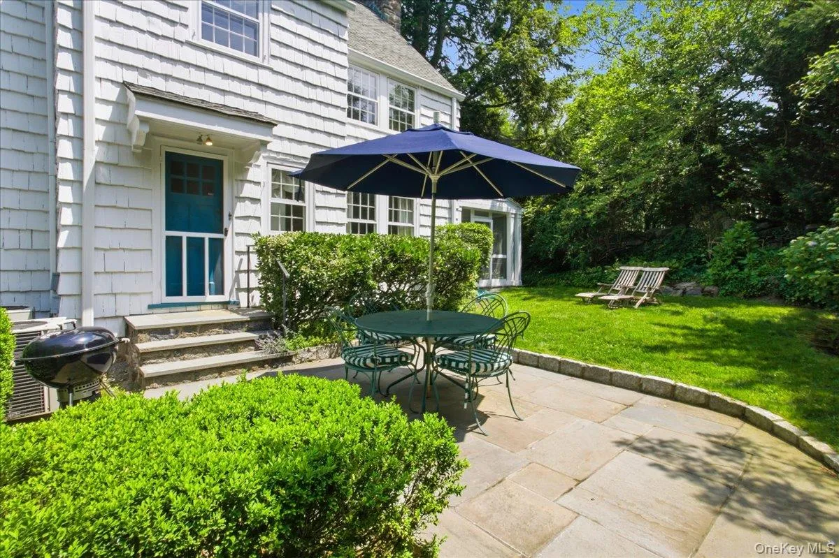 Stone patio featuring a curved border, surrounded by lush green shrubs and a grassy lawn Stone patio featuring a curved border, surrounded by lush green shrubs and a grassy lawn