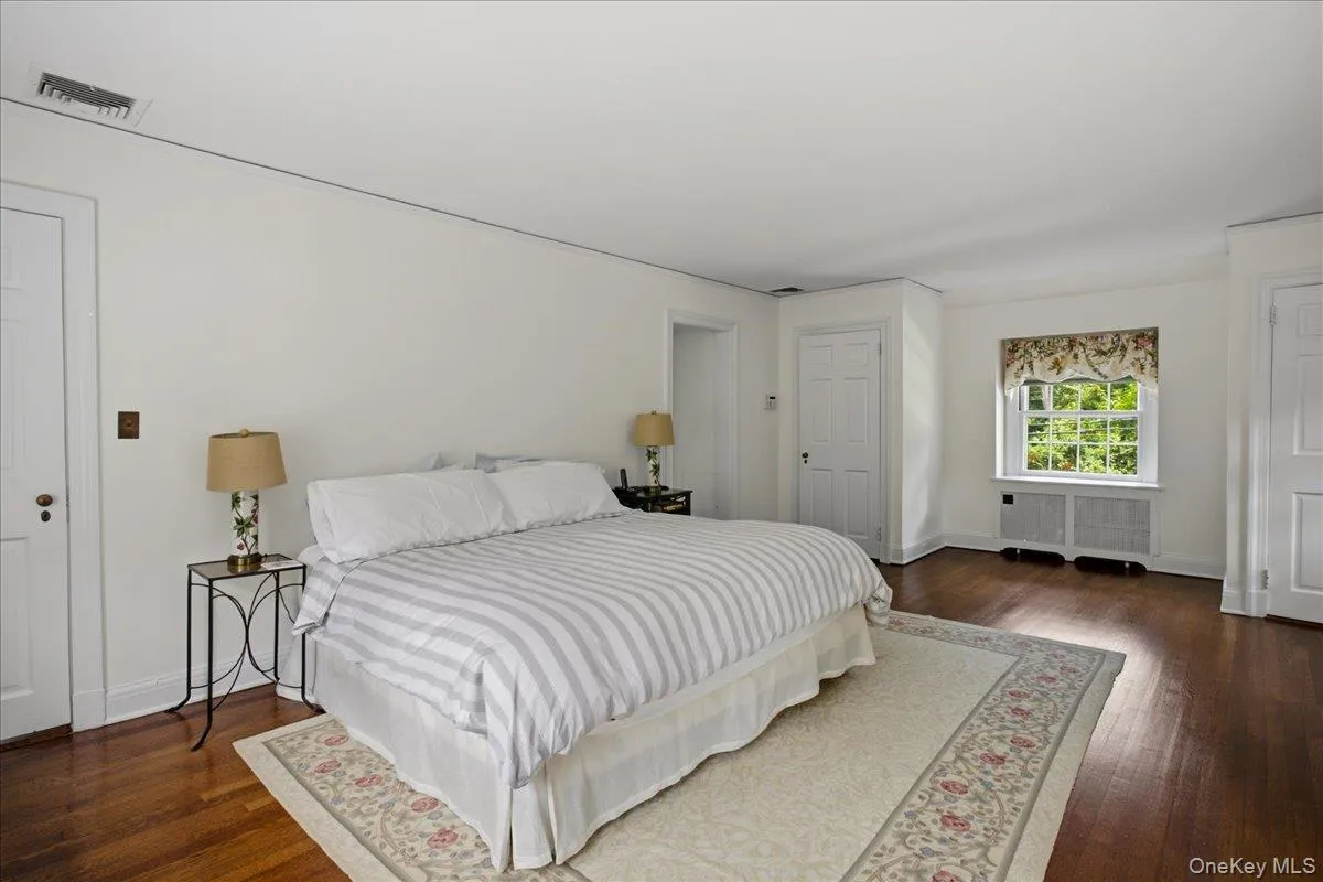 Spacious room featuring rich wood-finish flooring, white painted walls, and white trim Spacious room featuring rich wood-finish flooring, white painted walls, and white trim