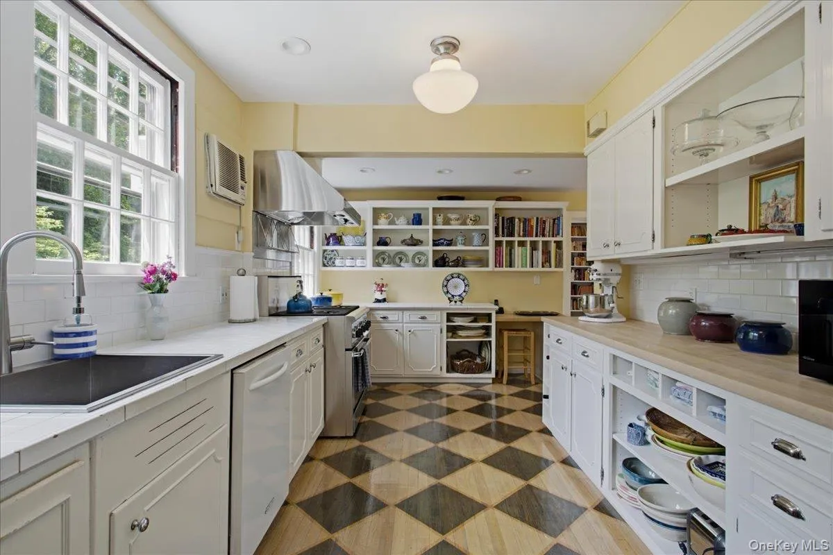 Kitchen featuring a checkerboard wood-finish floor, white cabinetry, and stainless-steel appliances Kitchen featuring a checkerboard wood-finish floor, white cabinetry, and stainless-steel appliances