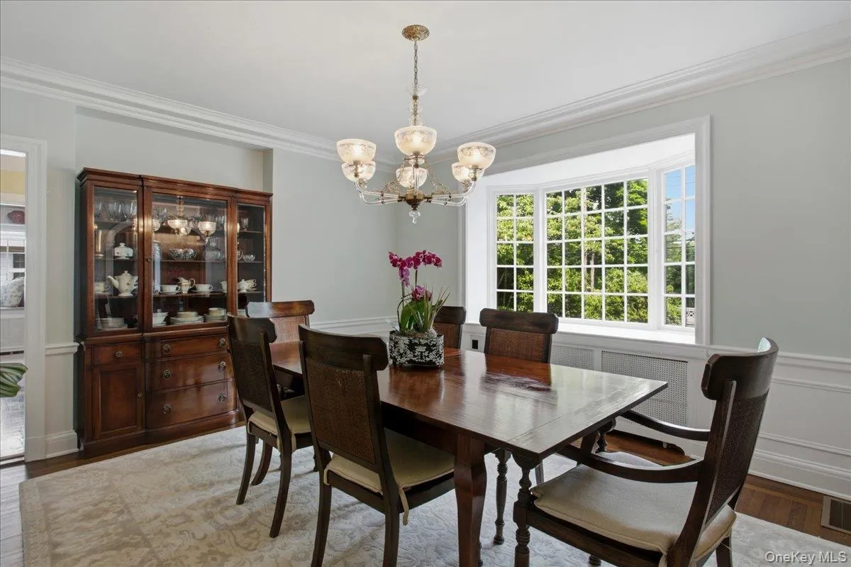 Dining room featuring a bay window, crown molding, chair rail, wood-finish flooring, and a chandelier Dining room featuring a bay window, crown molding, chair rail, wood-finish flooring, and a chandelier