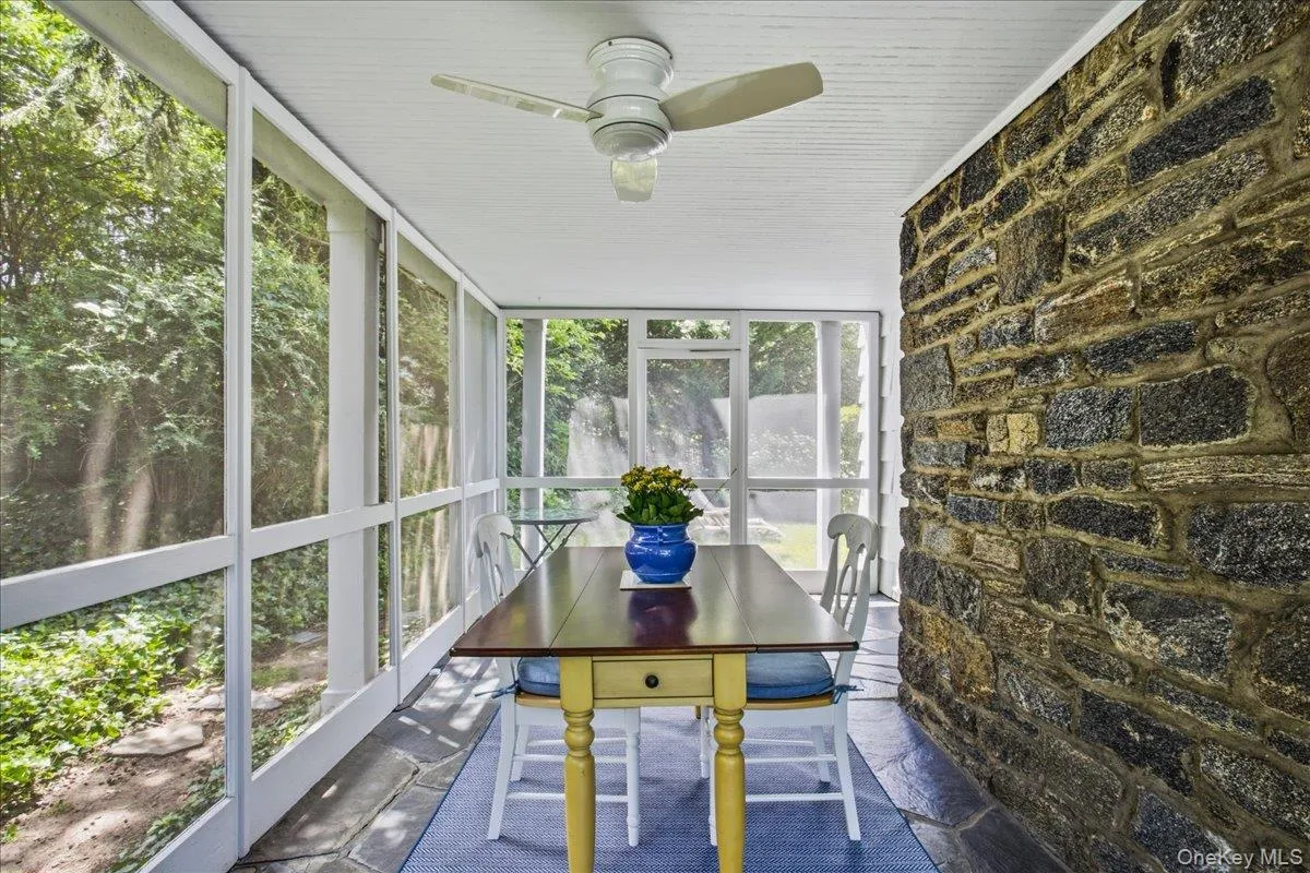 Inviting screened porch featuring a stone accent wall, slate flooring, and a paneled ceiling with a ceiling fan Inviting screened porch featuring a stone accent wall, slate flooring, and a paneled ceiling with a ceiling fan