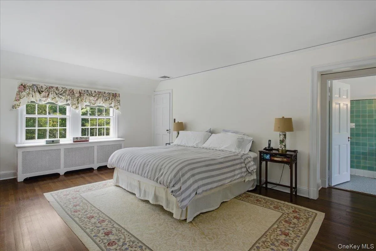 Bedroom featuring hardwood flooring, white walls, and a white paneled door Bedroom featuring hardwood flooring, white walls, and a white paneled door