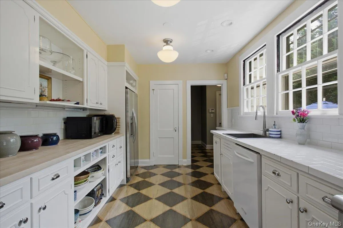 Country chef's kitchen ,featuring white cabinetry, butcher block and tile counter tops. Subway tile backsplash, stainless steel appliances, and checkerboard pattern flooring Country chef's kitchen ,featuring white cabinetry, butcher block and tile counter tops. Subway tile backsplash, stainless steel appliances, and checkerboard pattern flooring