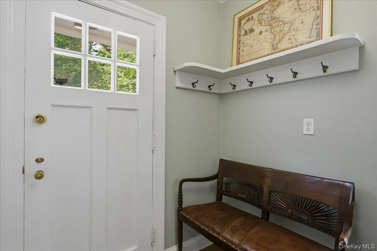 Entryway featuring a white paneled door with glass inserts, brass hardware, and light-toned wall paint Entryway featuring a white paneled door with glass inserts, brass hardware, and light-toned wall paint