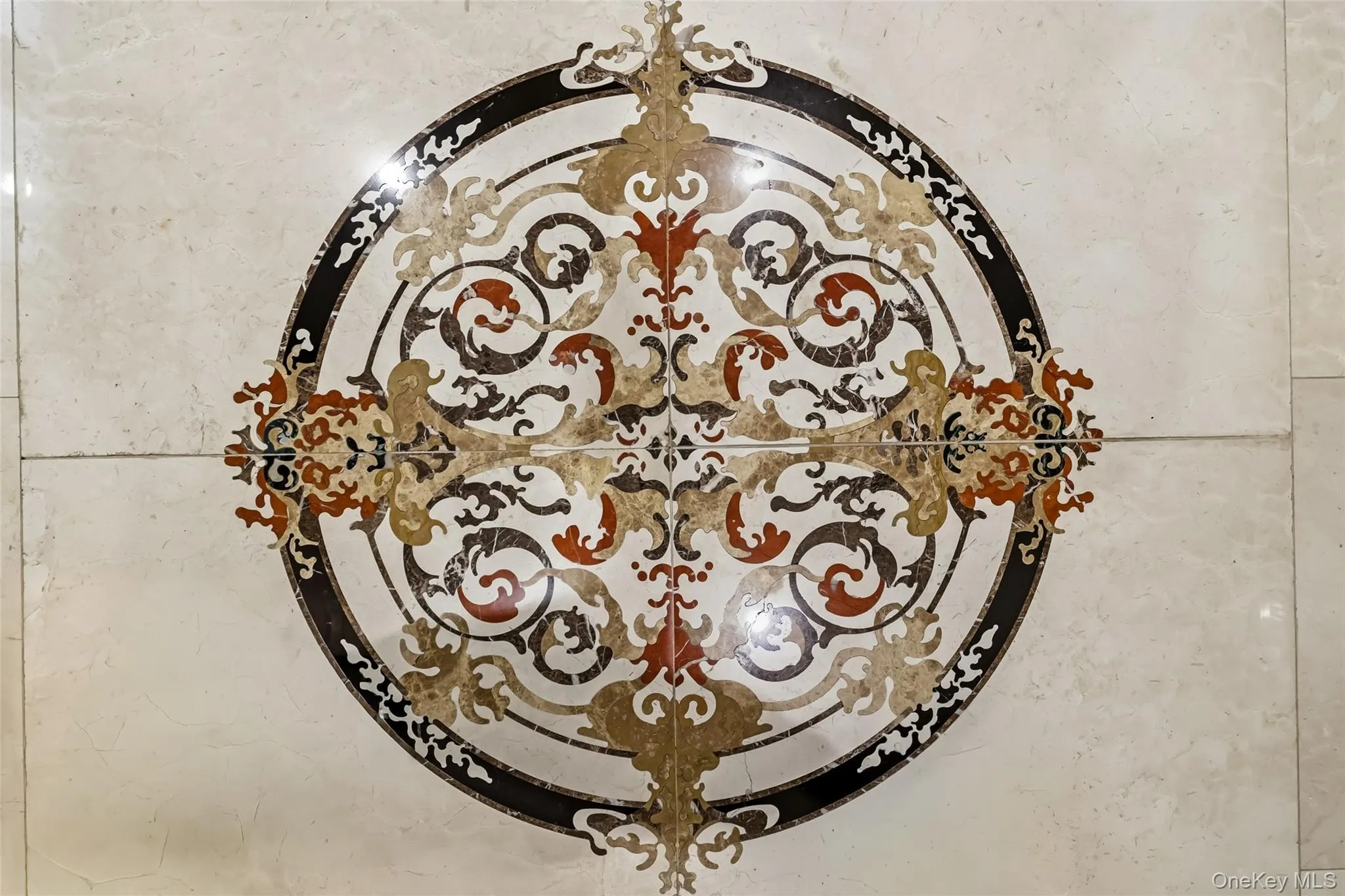 Decorative floor medallion featuring intricate scrollwork and a multi-tone palette, set into light-toned tile flooring Decorative floor medallion featuring intricate scrollwork and a multi-tone palette, set into light-toned tile flooring