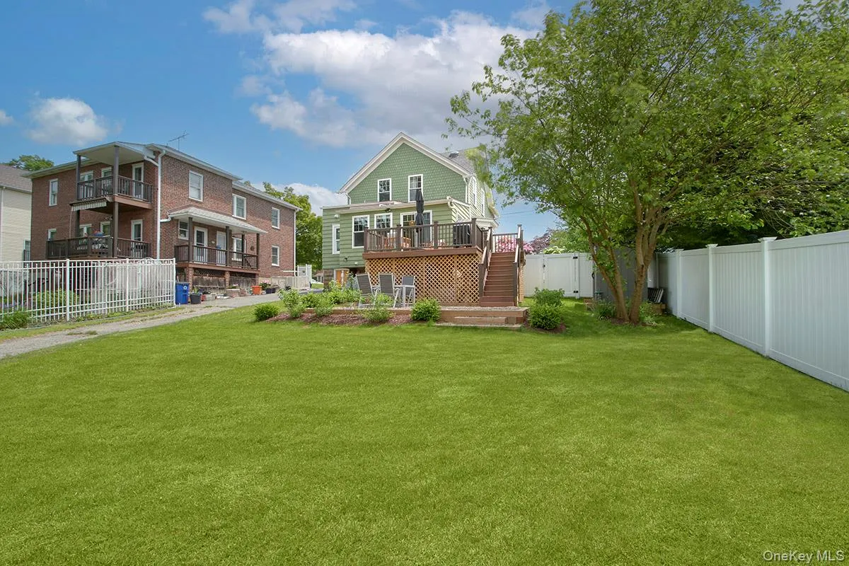 Back of property featuring stairs and a deck and sweeping yard Back of property featuring stairs and a deck and sweeping yard