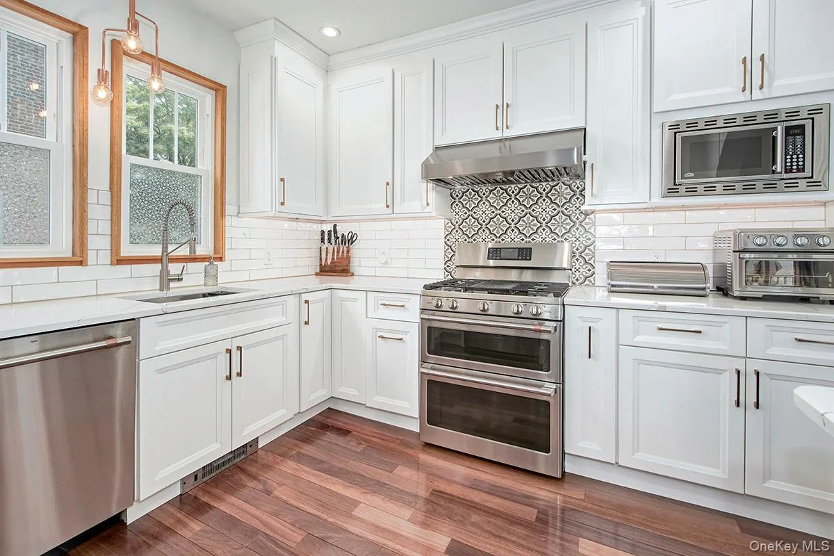 Kitchen featuring appliances with stainless steel finishes, under cabinet range hood, a sink, recessed lighting, and white cabinetry Kitchen featuring appliances with stainless steel finishes, under cabinet range hood, a sink, recessed lighting, and white cabinetry