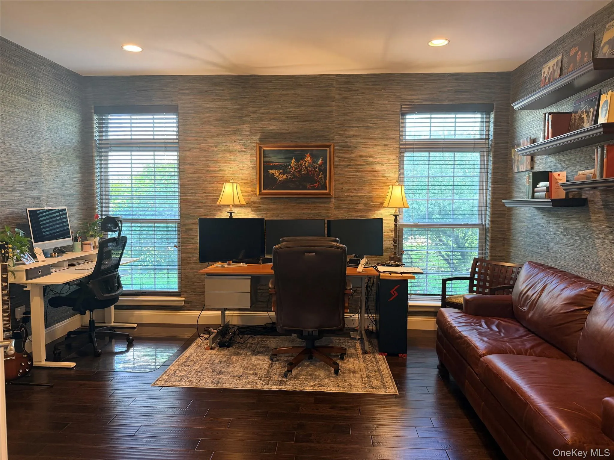 Room featuring dark wood-finish flooring, textured wall covering, recessed lighting, and two windows with blinds Room featuring dark wood-finish flooring, textured wall covering, recessed lighting, and two windows with blinds