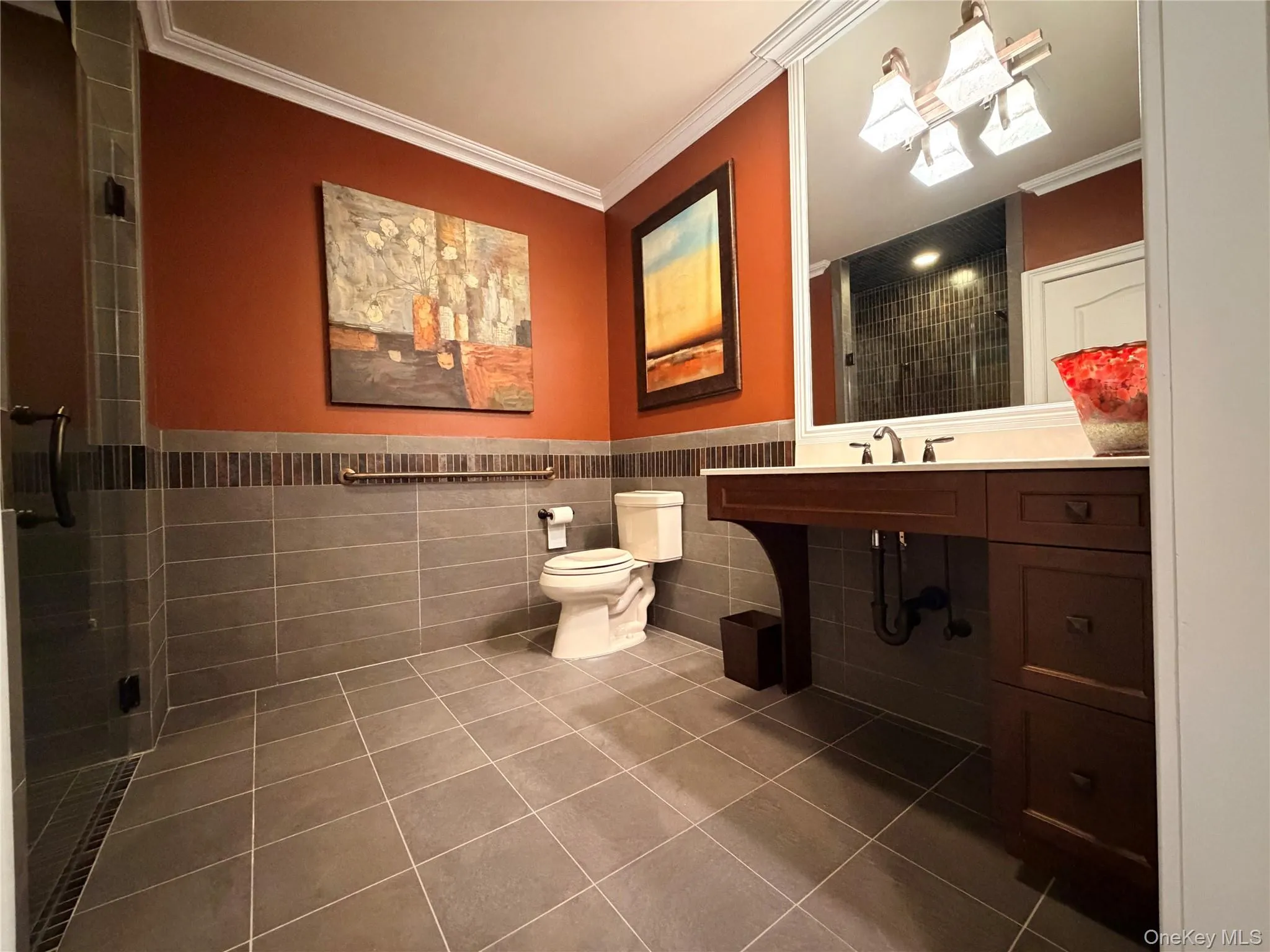 Spacious bathroom featuring large format floor tiles, a dark wood-finish vanity with countertop, and a walk-in shower with glass enclosure Spacious bathroom featuring large format floor tiles, a dark wood-finish vanity with countertop, and a walk-in shower with glass enclosure