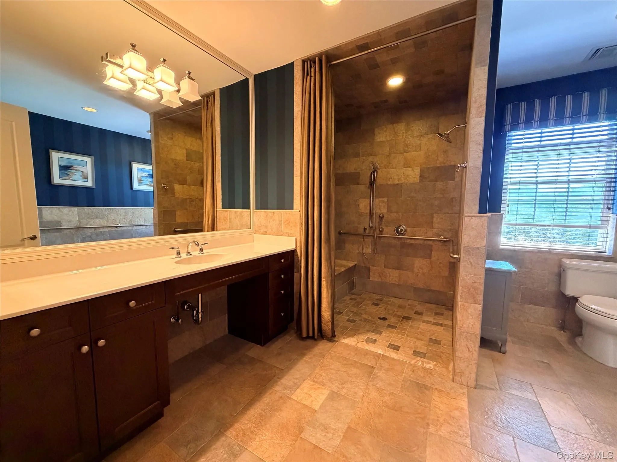 Spacious bathroom featuring a large vanity with ample countertop space, a walk-in shower with integrated bench seating, and patterned floor tiling Spacious bathroom featuring a large vanity with ample countertop space, a walk-in shower with integrated bench seating, and patterned floor tiling