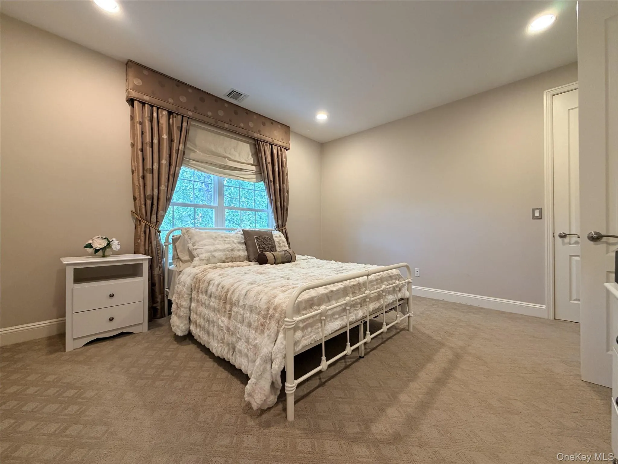Carpeted room featuring a window with custom drapery, recessed lighting, and a paneled door Carpeted room featuring a window with custom drapery, recessed lighting, and a paneled door