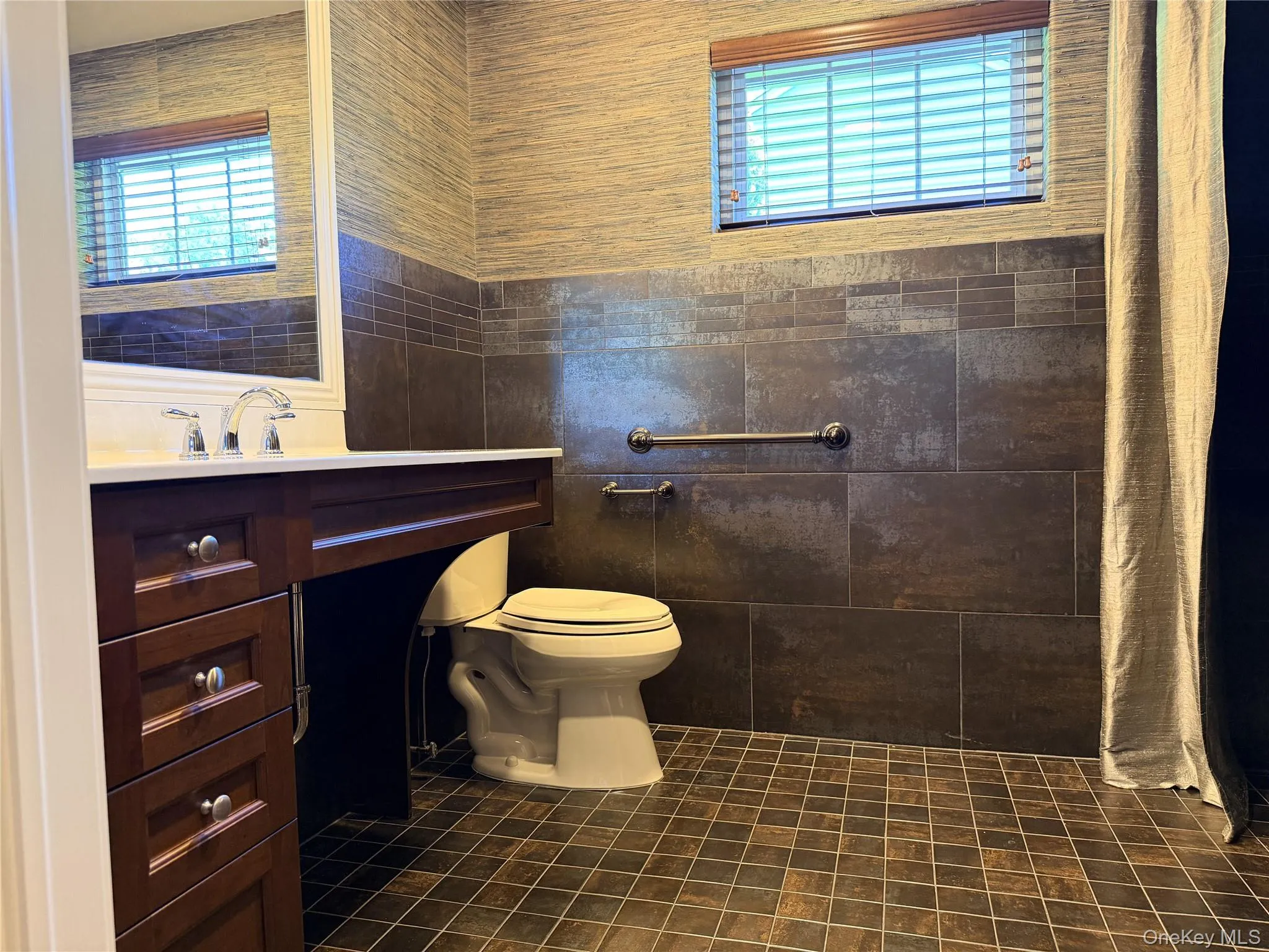 Bathroom featuring a dark wood vanity with a white countertop and chrome fixtures Bathroom featuring a dark wood vanity with a white countertop and chrome fixtures
