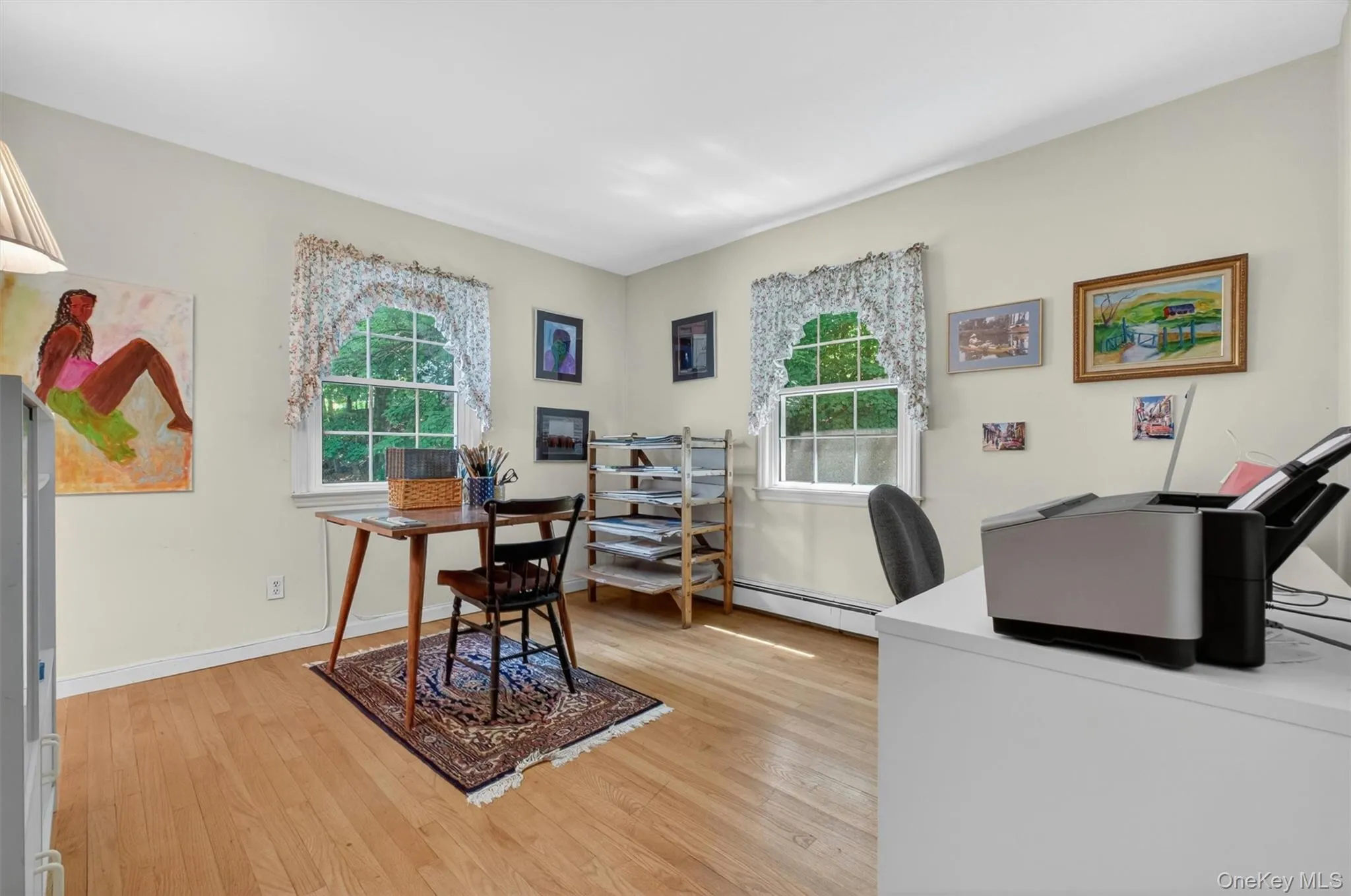 Bedroom #2 (used as office) w/light-toned walls, wood-finish flooring, two double-hung windows, and white trim baseboards Bedroom #2 (used as office) w/light-toned walls, wood-finish flooring, two double-hung windows, and white trim baseboards