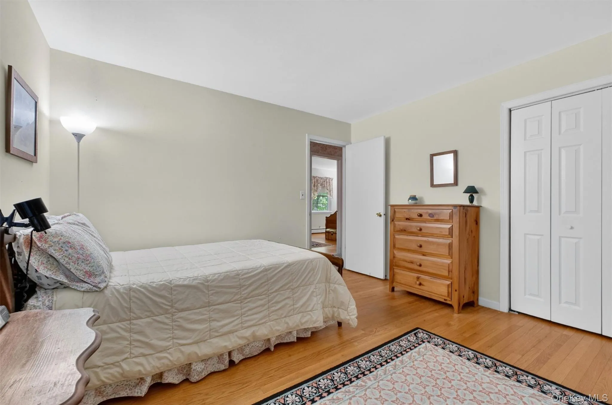 Bedroom #3 featuring wood-finish flooring, light-colored walls, a white ceiling, and a paneled bifold closet door Bedroom #3 featuring wood-finish flooring, light-colored walls, a white ceiling, and a paneled bifold closet door