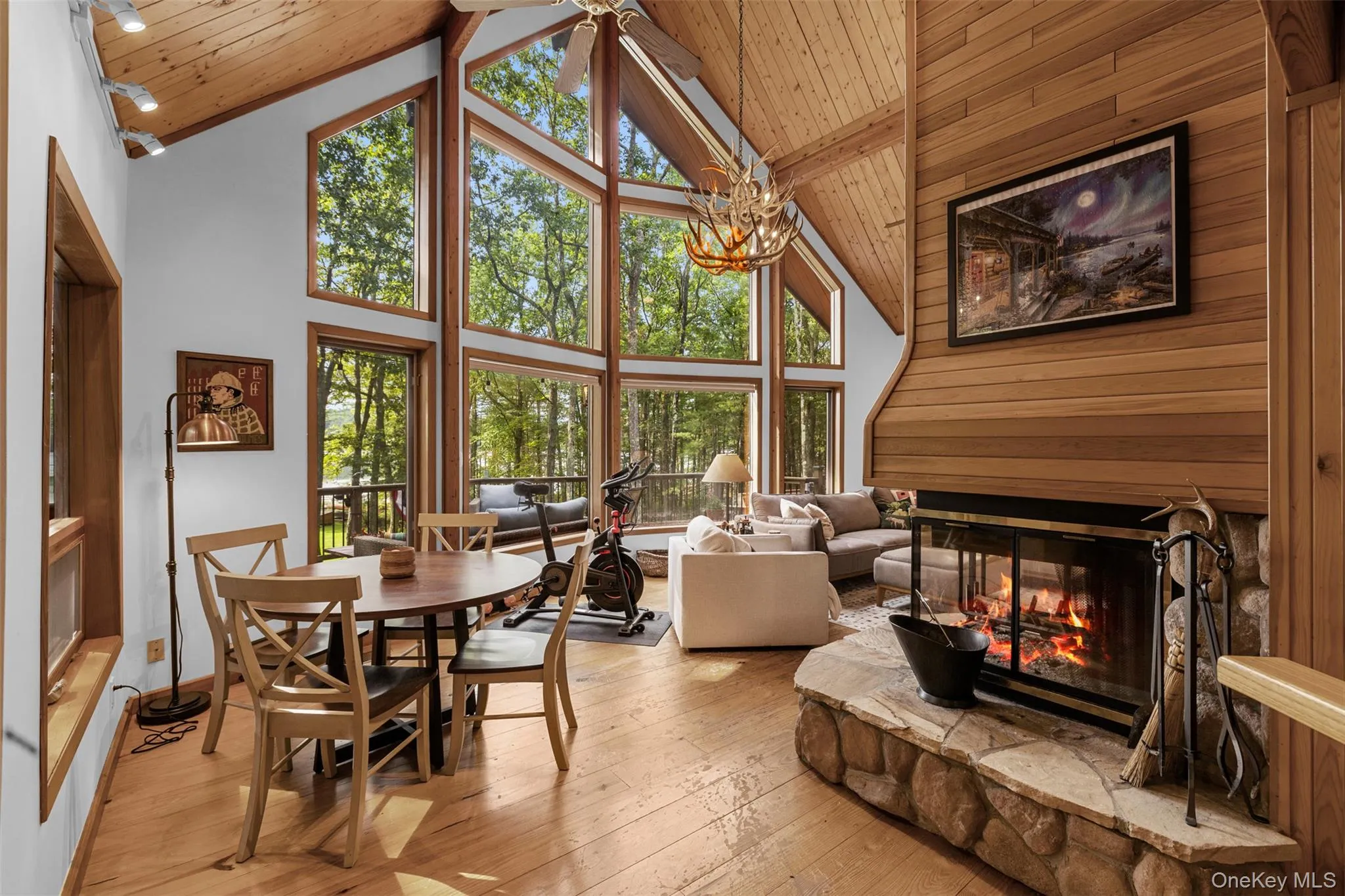 Dining area featuring high vaulted ceiling, a multi sided fireplace, a wooden ceiling with exposed beams, hardwood / wood-style floors, and wooden walls Dining area featuring high vaulted ceiling, a multi sided fireplace, a wooden ceiling with exposed beams, hardwood / wood-style floors, and wooden walls