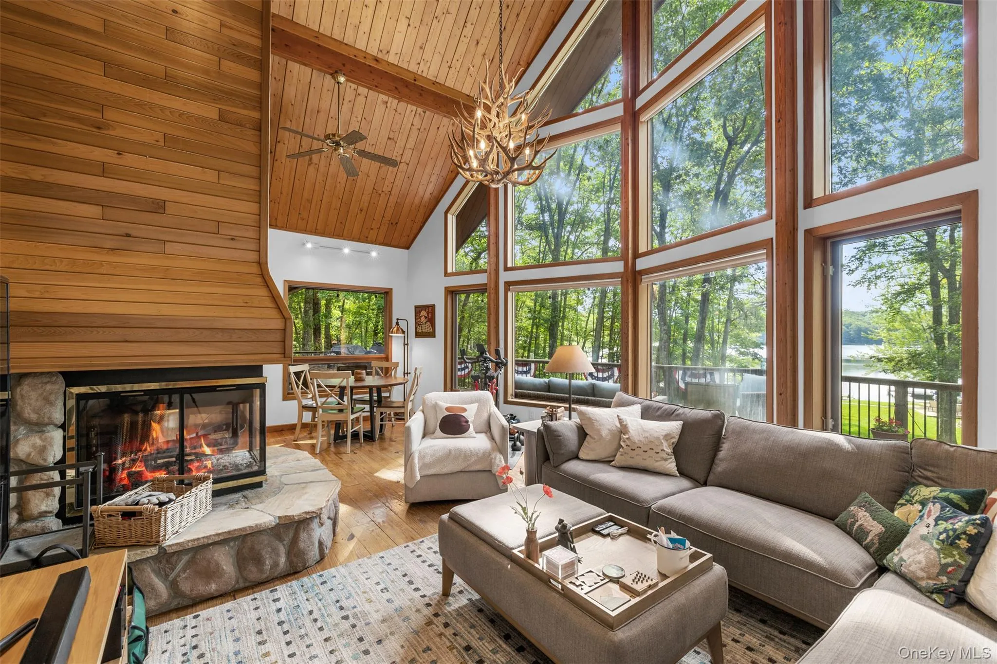 Living room with high vaulted ceiling, wood walls, hardwood / wood-style floors, a stone fireplace, and a chandelier Living room with high vaulted ceiling, wood walls, hardwood / wood-style floors, a stone fireplace, and a chandelier