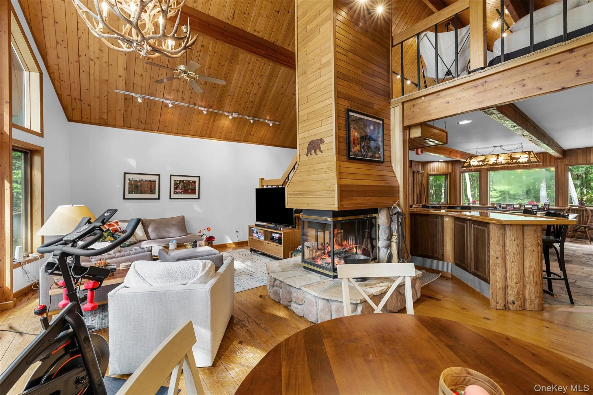 Living area featuring a wood ceiling with exposed beams, wood-type flooring, a chandelier, track lighting, and high vaulted ceiling Living area featuring a wood ceiling with exposed beams, wood-type flooring, a chandelier, track lighting, and high vaulted ceiling