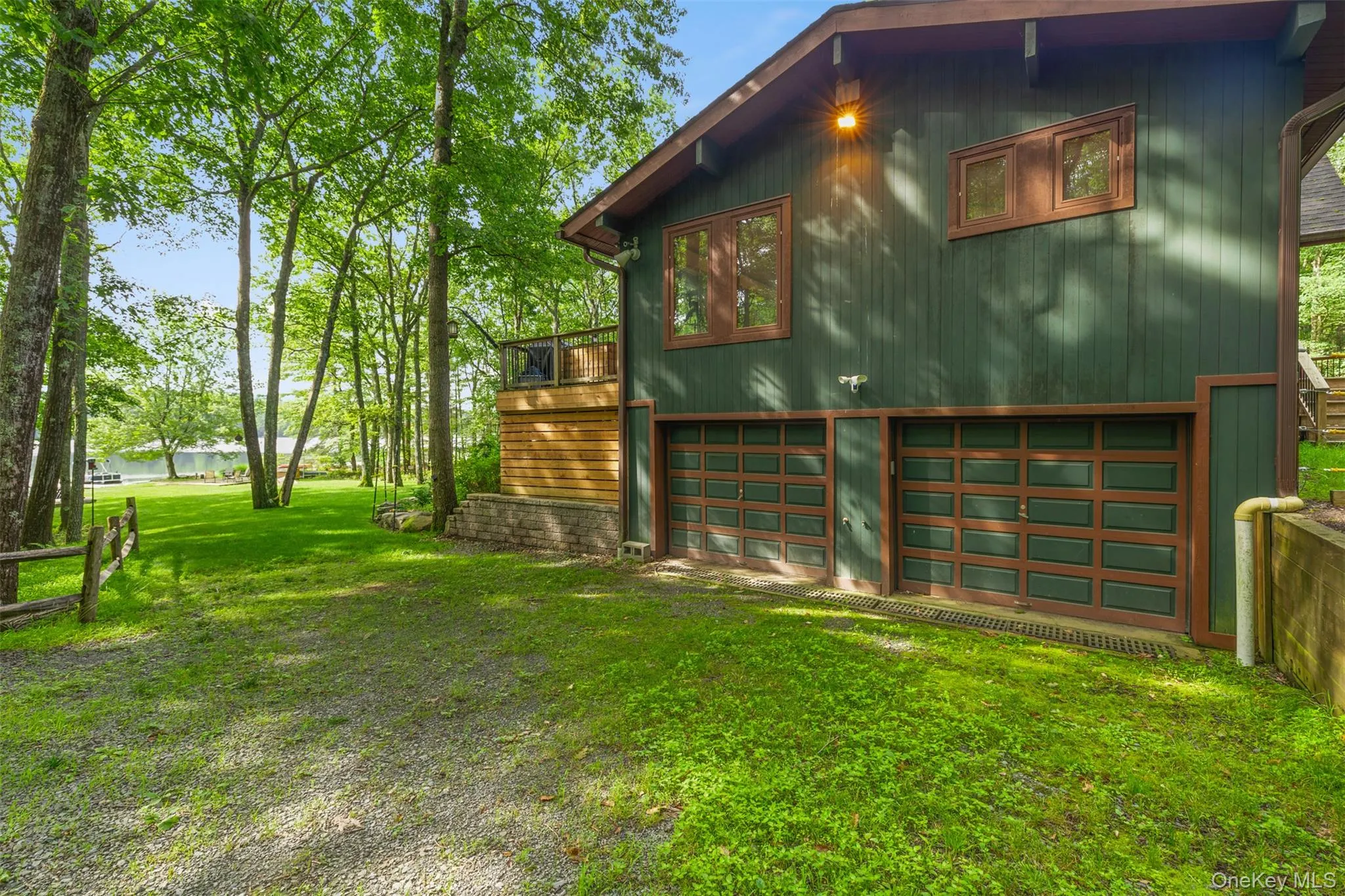 View of side of home with a yard, an attached garage, driveway, and a water view View of side of home with a yard, an attached garage, driveway, and a water view