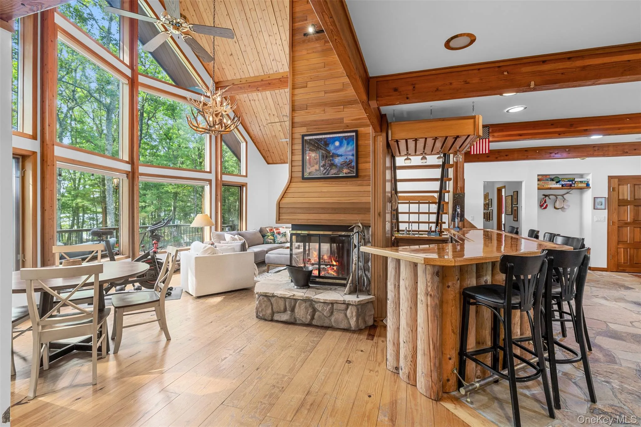 Kitchen featuring beamed ceiling, a multi sided fireplace, high vaulted ceiling, a ceiling fan, and a kitchen breakfast bar Kitchen featuring beamed ceiling, a multi sided fireplace, high vaulted ceiling, a ceiling fan, and a kitchen breakfast bar
