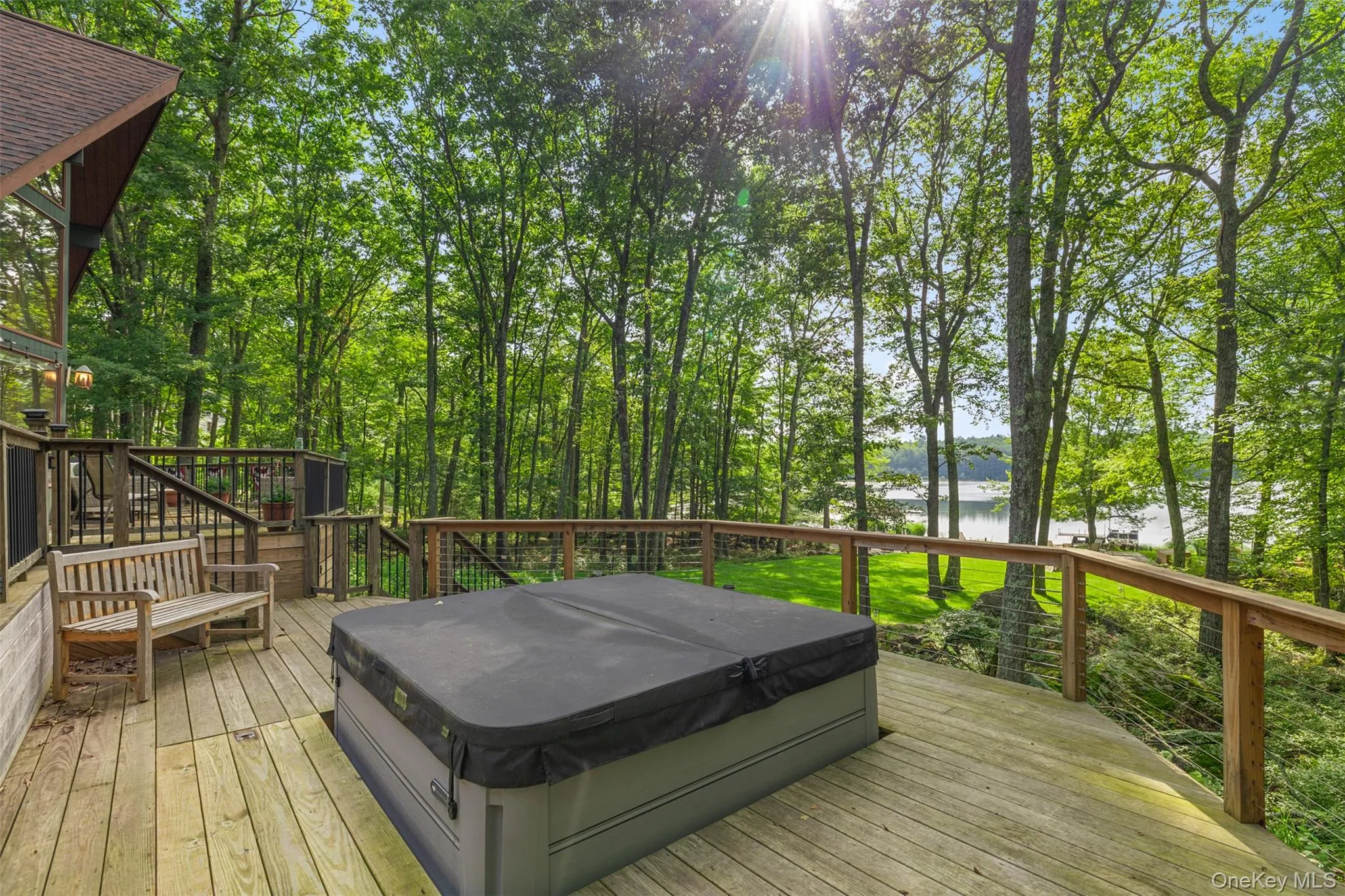 Deck featuring a covered hot tub and a water view Deck featuring a covered hot tub and a water view