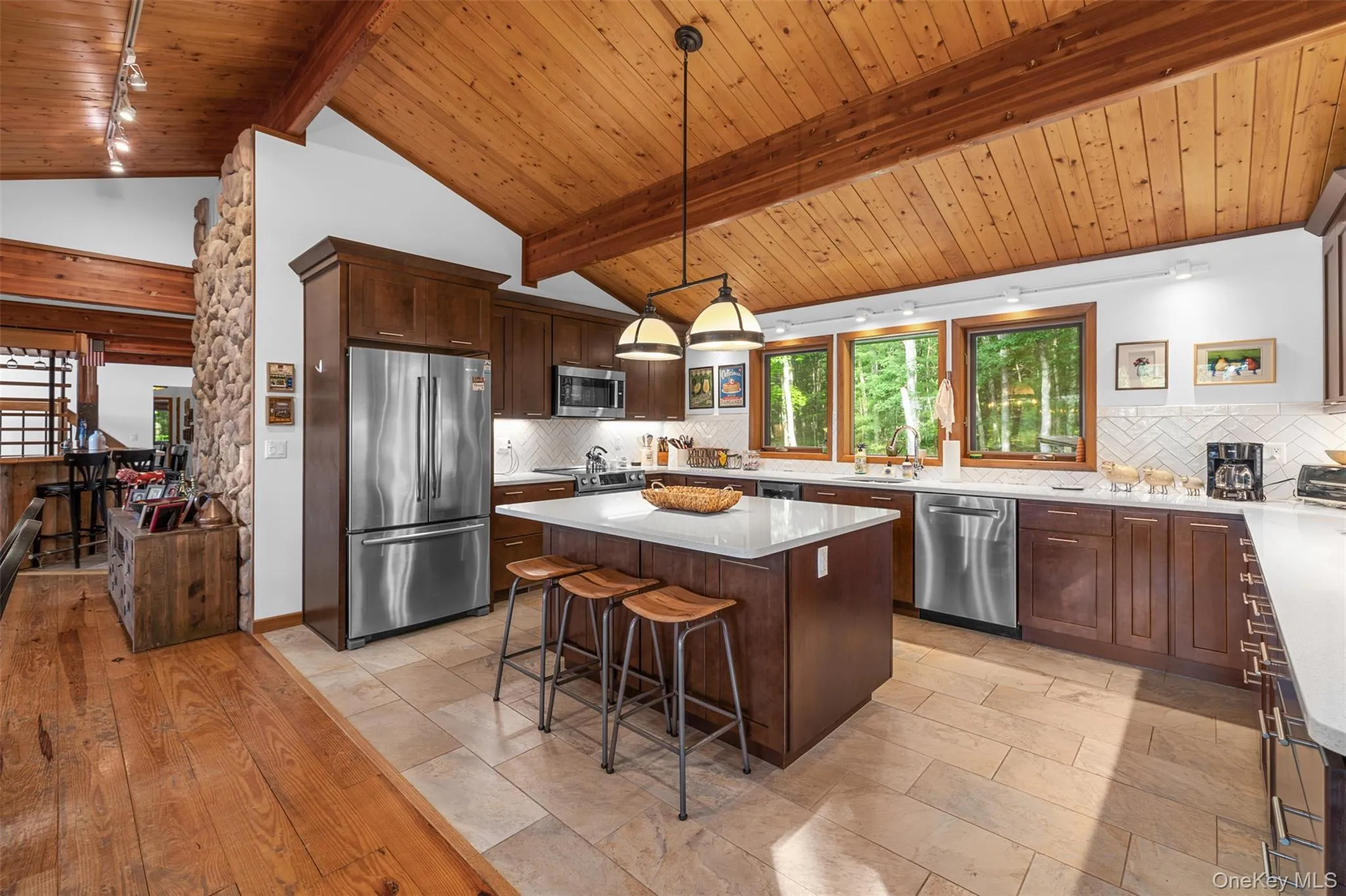 Kitchen featuring stainless steel appliances, wooden ceiling, a center island, a breakfast bar, and tasteful backsplash Kitchen featuring stainless steel appliances, wooden ceiling, a center island, a breakfast bar, and tasteful backsplash