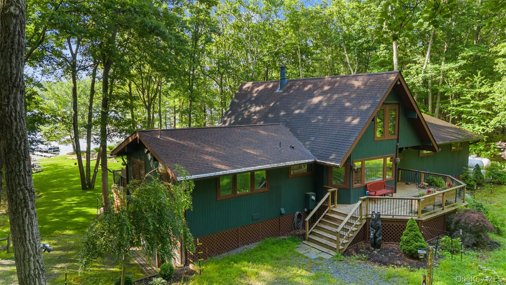 View of front of house with a shingled roof, a wooden deck, a front yard, and stairway View of front of house with a shingled roof, a wooden deck, a front yard, and stairway