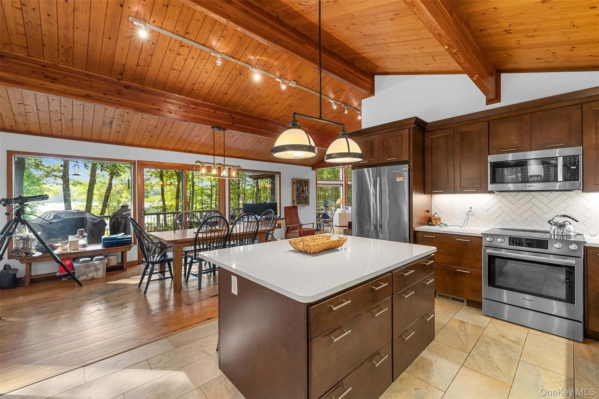 Kitchen featuring stainless steel appliances, wood ceiling, rail lighting, backsplash, and light countertops Kitchen featuring stainless steel appliances, wood ceiling, rail lighting, backsplash, and light countertops