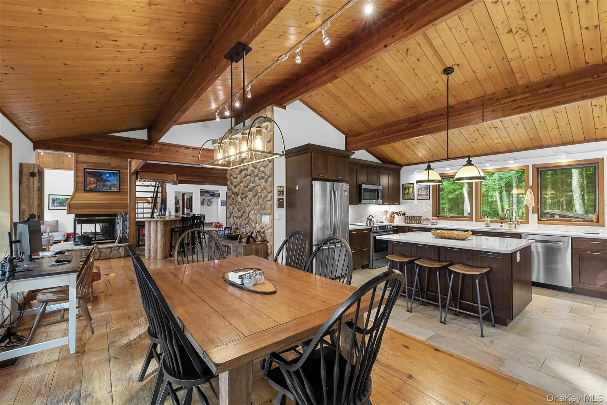 Dining area with track lighting, light wood finished floors, wood ceiling, a chandelier, and a multi sided fireplace Dining area with track lighting, light wood finished floors, wood ceiling, a chandelier, and a multi sided fireplace
