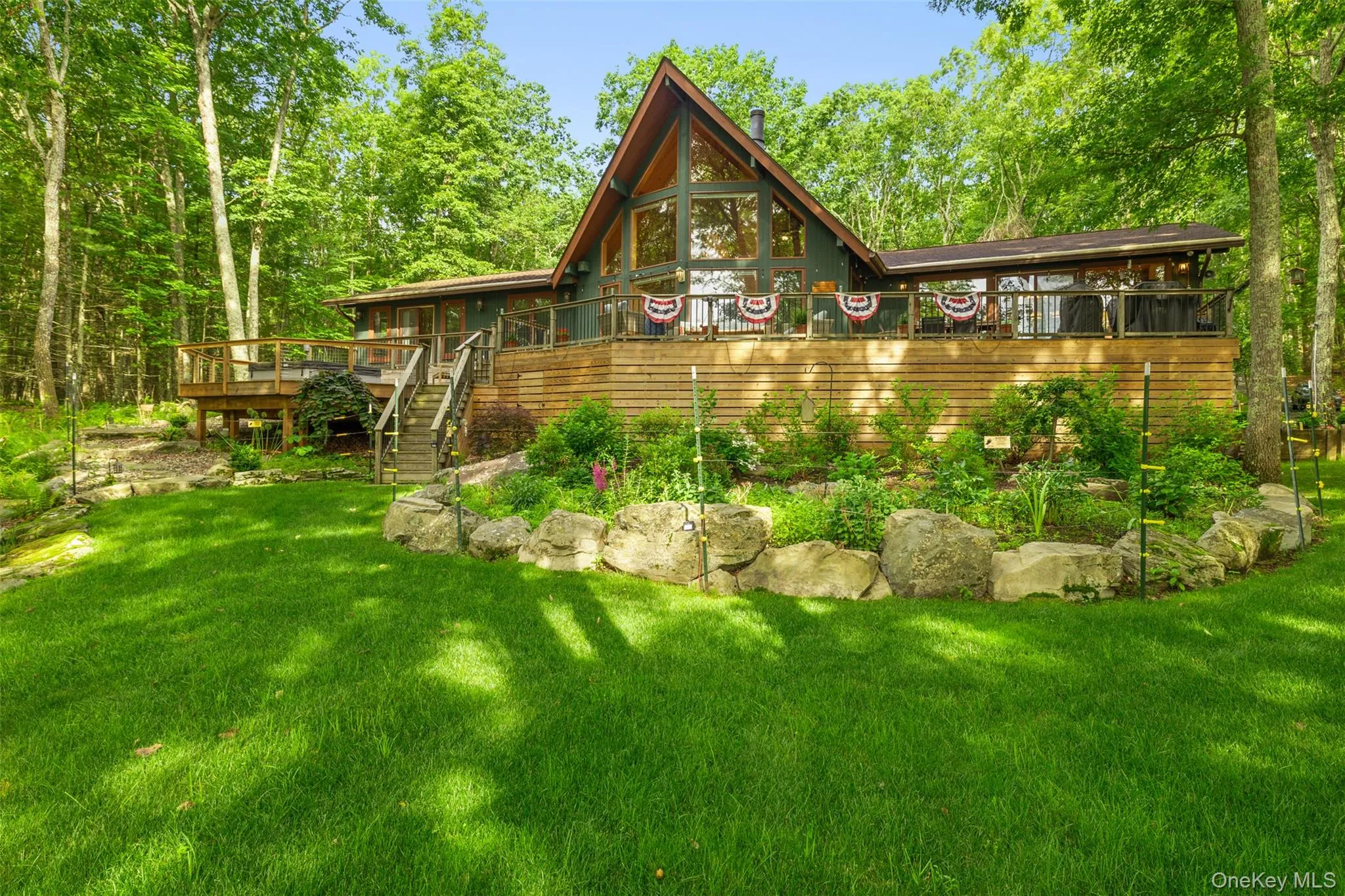 Rear view of property with a deck, a lawn, and stairs Rear view of property with a deck, a lawn, and stairs