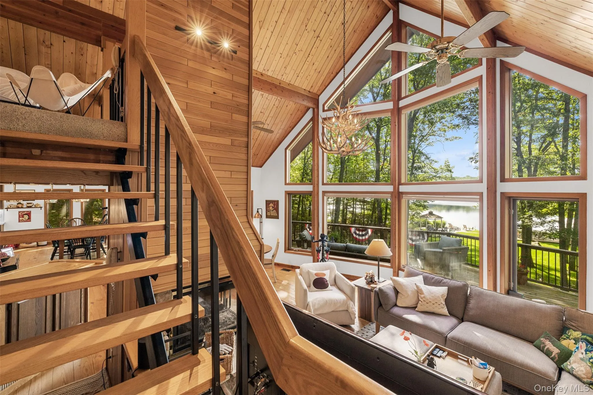 Living area with ceiling fan, high vaulted ceiling, a wood ceiling with exposed beams, a water view, and stairway Living area with ceiling fan, high vaulted ceiling, a wood ceiling with exposed beams, a water view, and stairway