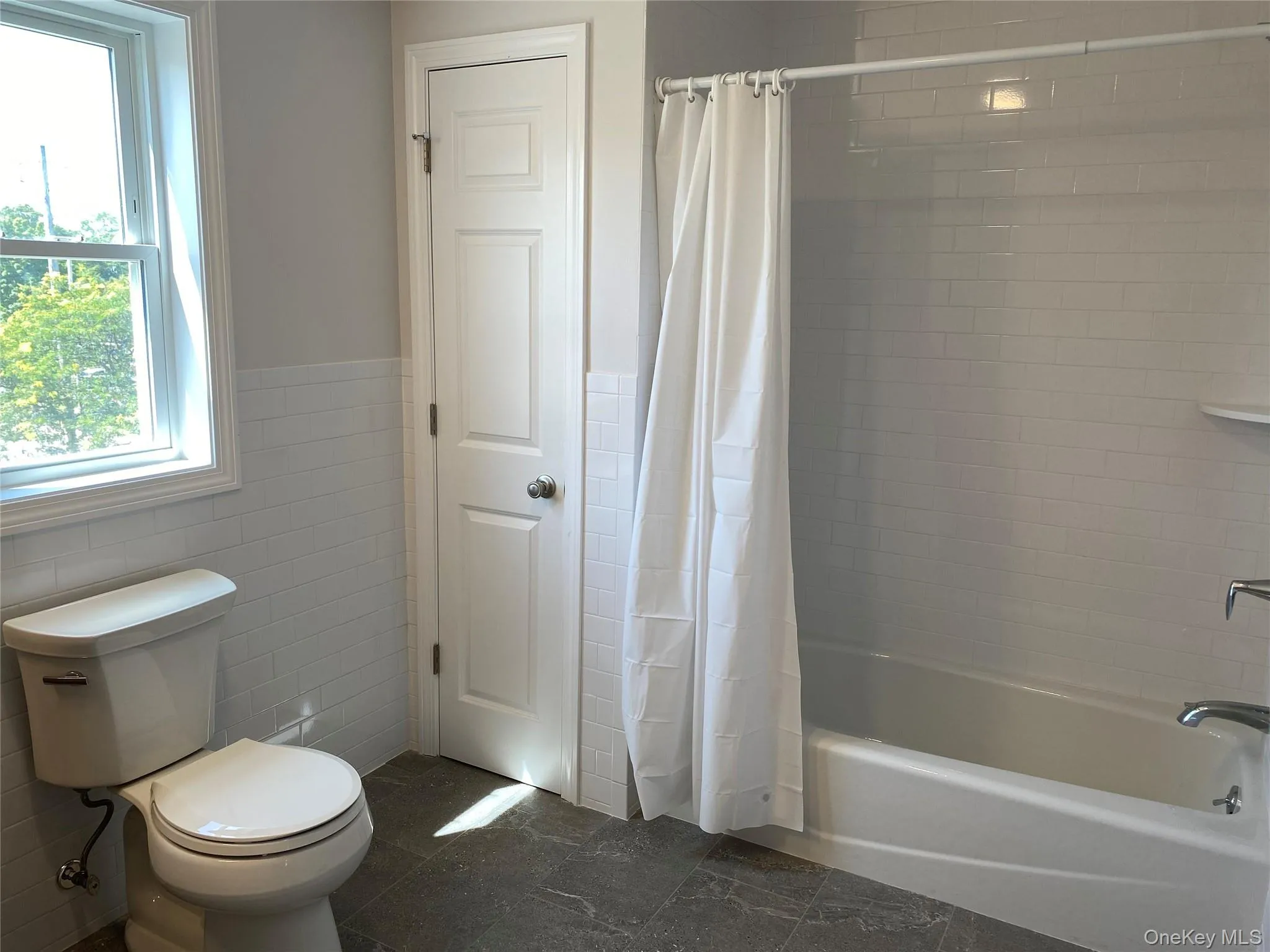 Full bathroom featuring tile walls, shower / tub combo Full bathroom featuring tile walls, shower / tub combo