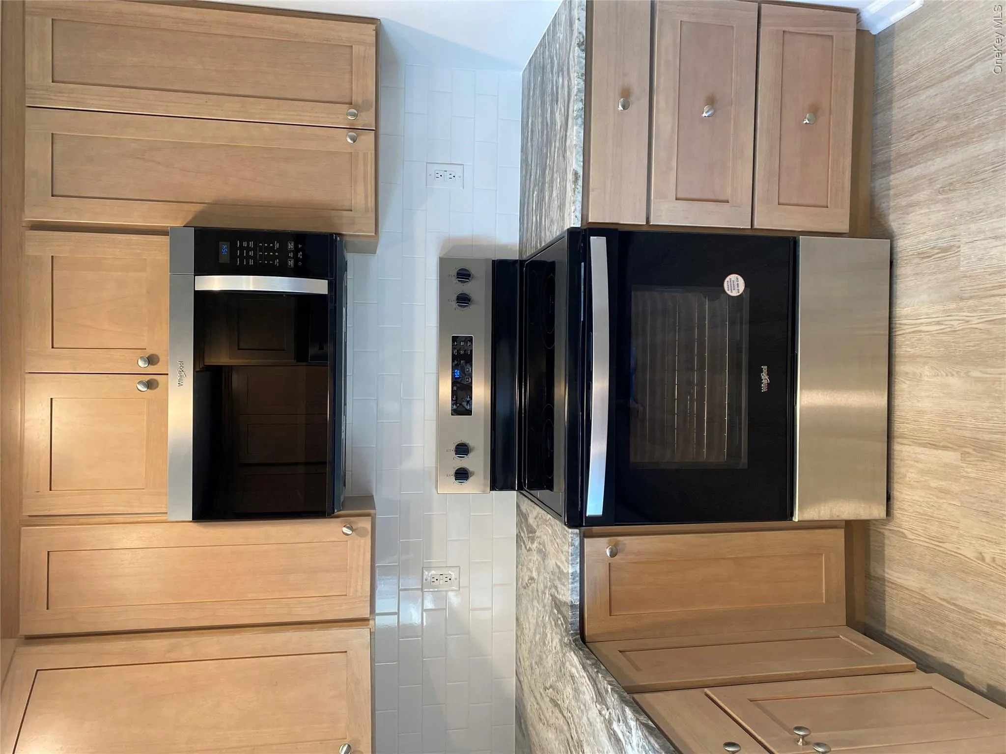 Kitchen with electric range, decorative backsplash, light stone countertops, brown cabinets, and light wood-style flooring Kitchen with electric range, decorative backsplash, light stone countertops, brown cabinets, and light wood-style flooring