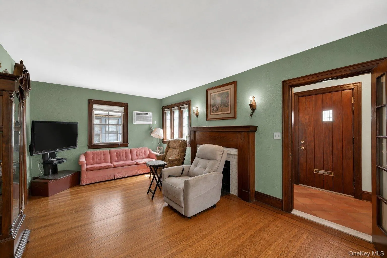 Inviting living area featuring wood-finish flooring, a wood-trimmed fireplace, and sage green walls Inviting living area featuring wood-finish flooring, a wood-trimmed fireplace, and sage green walls