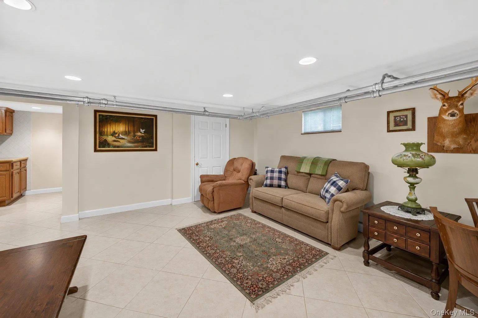 Spacious living area featuring light-toned tile flooring, recessed ceiling lighting, and neutral wall tones Spacious living area featuring light-toned tile flooring, recessed ceiling lighting, and neutral wall tones