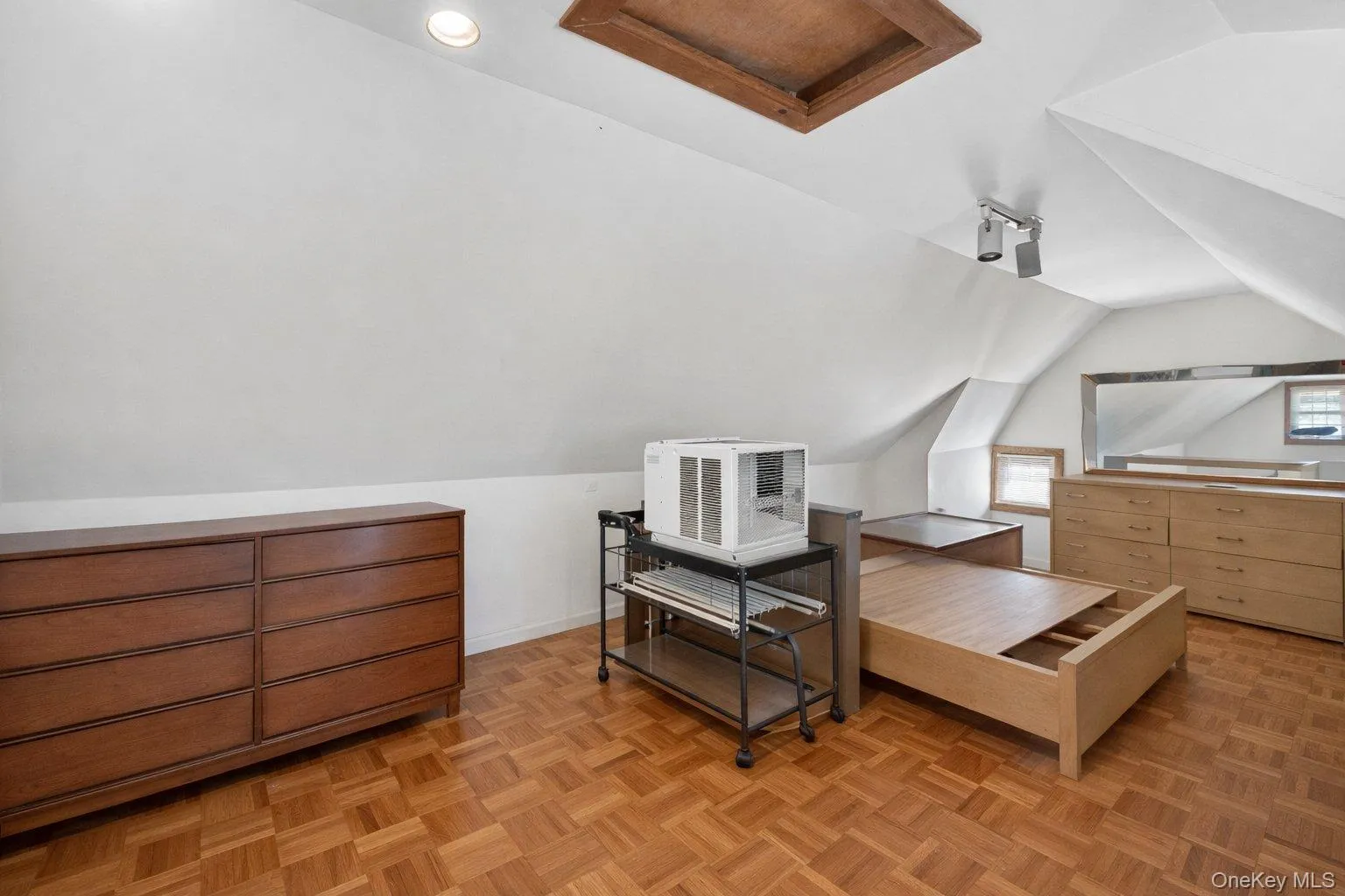 Room featuring sloped ceilings, parquet wood-finish flooring, recessed lighting, and a wood-frame attic access hatch Room featuring sloped ceilings, parquet wood-finish flooring, recessed lighting, and a wood-frame attic access hatch