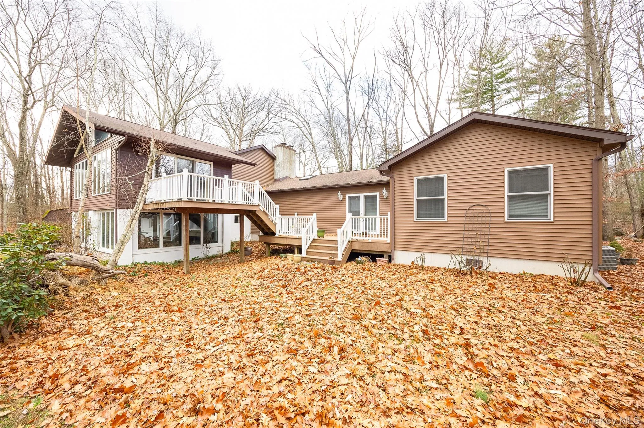Back of property featuring a wooden deck, stairway, and a chimney Back of property featuring a wooden deck, stairway, and a chimney