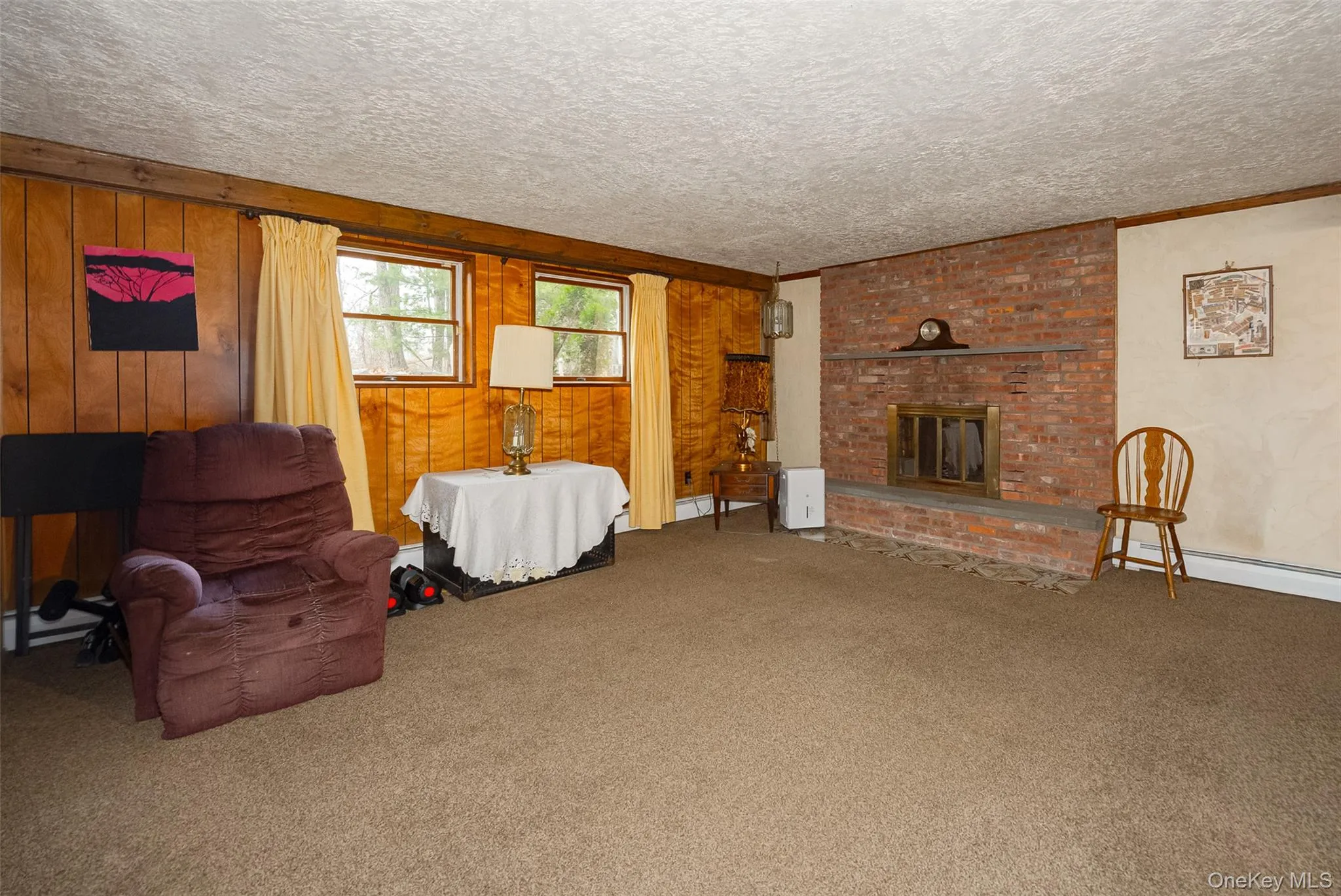 Living area with a fireplace, carpet flooring, wood walls, and a textured ceiling Living area with a fireplace, carpet flooring, wood walls, and a textured ceiling