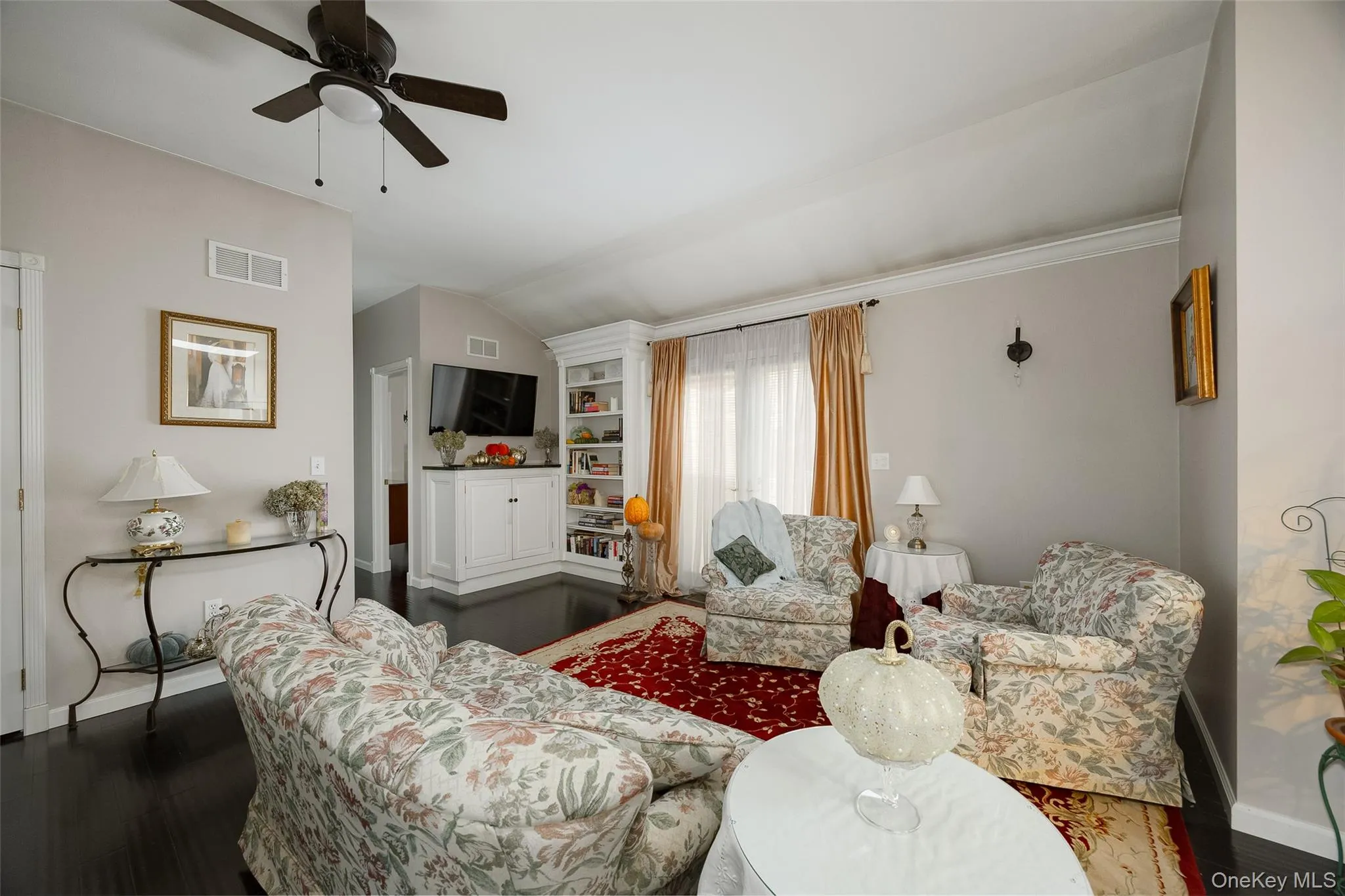 Living area with wood finished floors, built in features, a ceiling fan, and vaulted ceiling Living area with wood finished floors, built in features, a ceiling fan, and vaulted ceiling