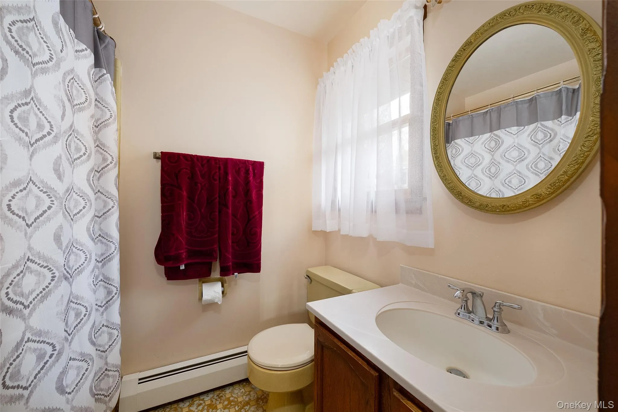 Bathroom featuring baseboard heating, vanity, and a shower with shower curtain Bathroom featuring baseboard heating, vanity, and a shower with shower curtain