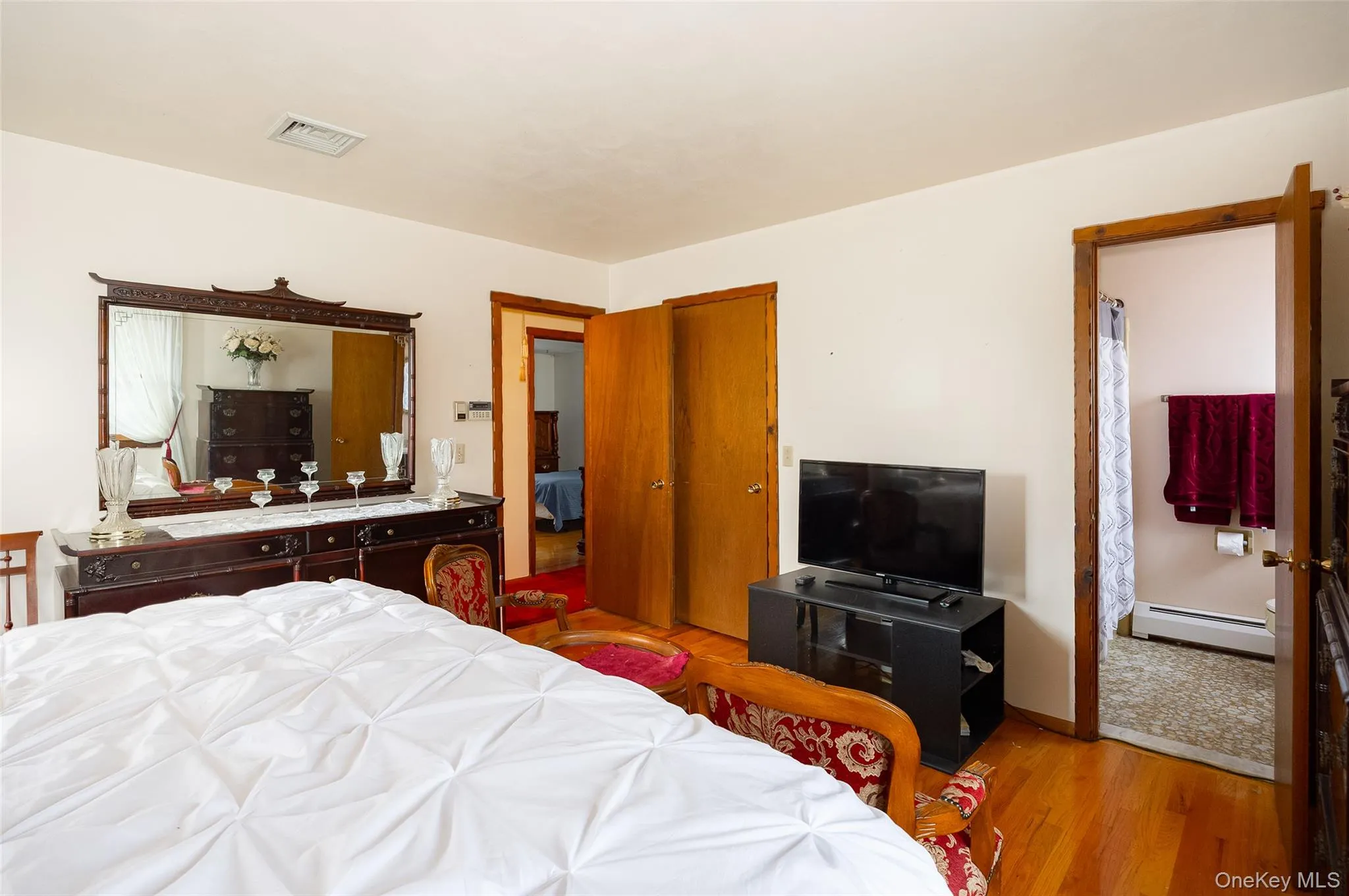 Bedroom featuring baseboard heating and wood finished floors Bedroom featuring baseboard heating and wood finished floors