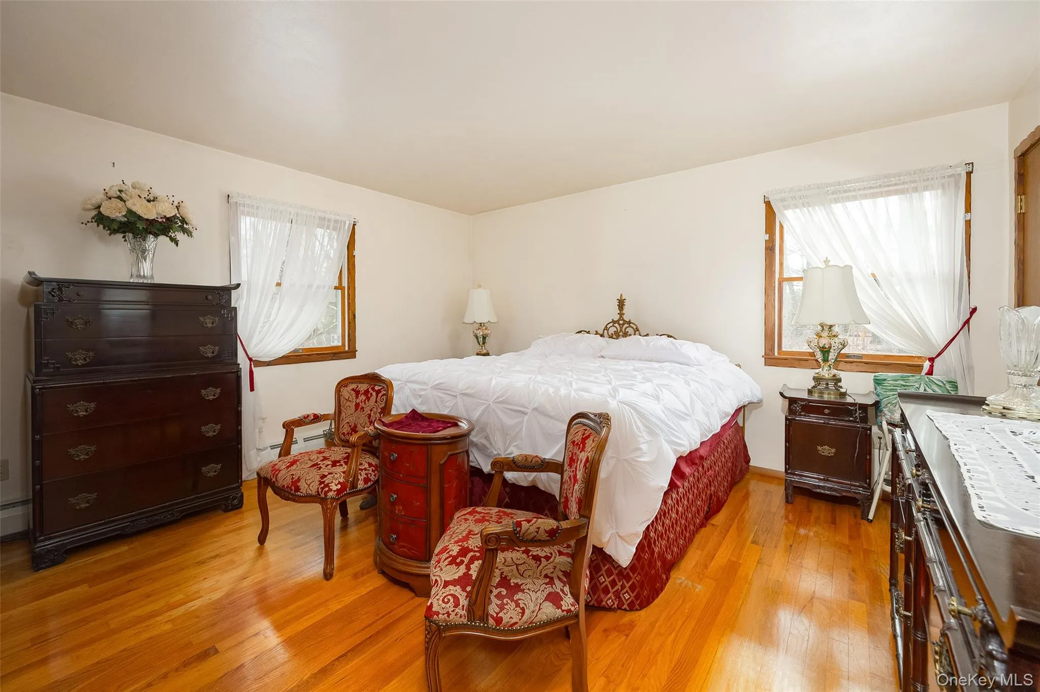 Bedroom with multiple windows, light wood-style floors, and baseboard heating Bedroom with multiple windows, light wood-style floors, and baseboard heating