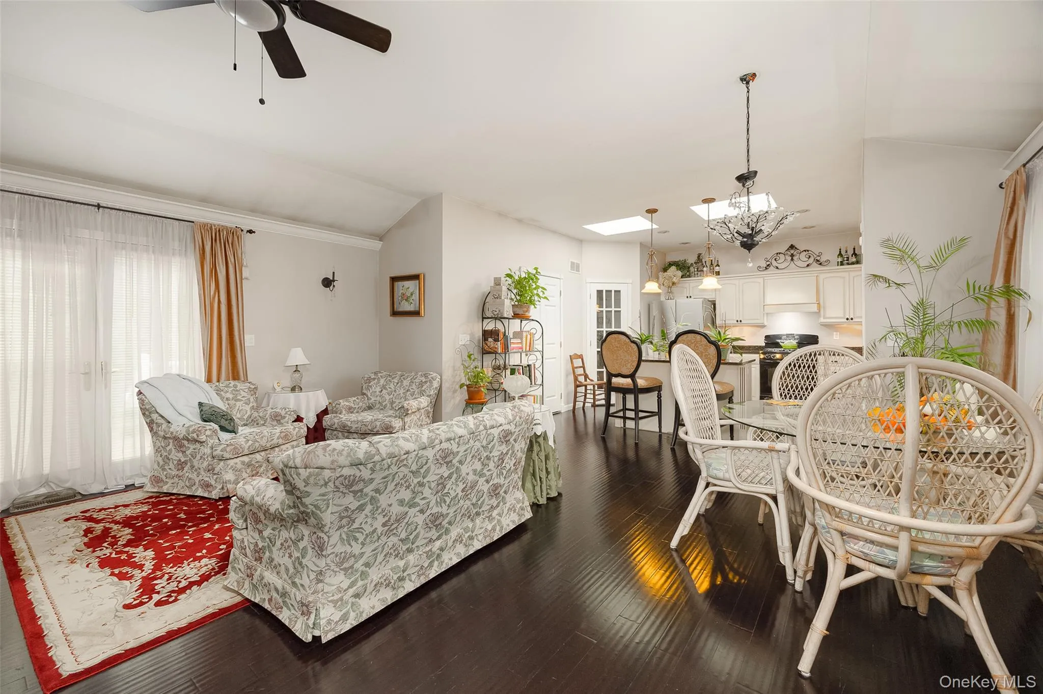 Living room featuring a ceiling fan, a skylight, dark wood finished floors, and vaulted ceiling Living room featuring a ceiling fan, a skylight, dark wood finished floors, and vaulted ceiling
