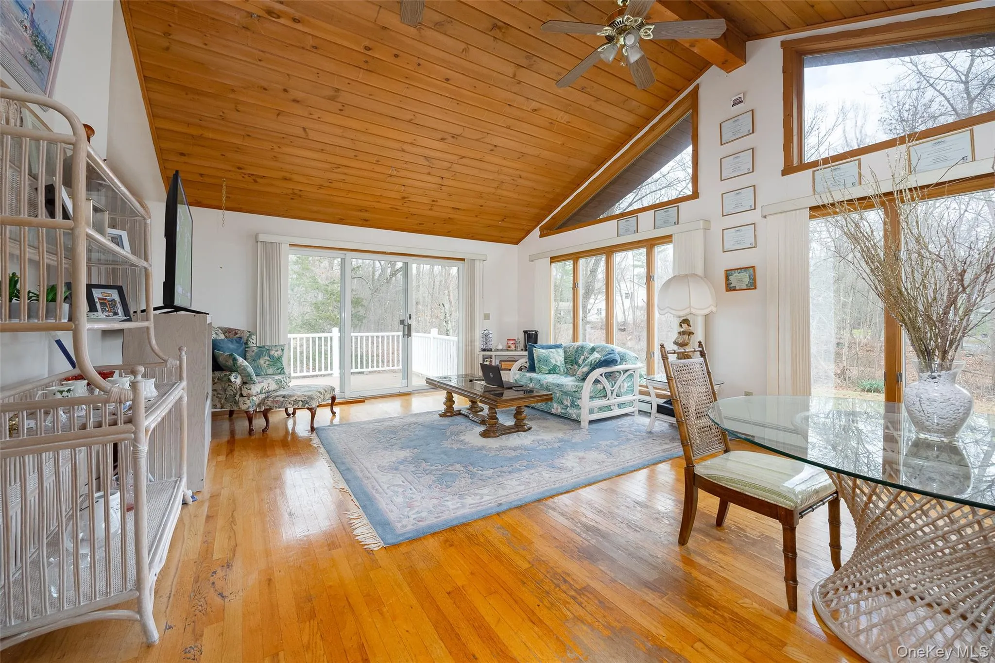 Living area featuring high vaulted ceiling, light wood-type flooring, a ceiling fan, and a wooden ceiling with exposed beams Living area featuring high vaulted ceiling, light wood-type flooring, a ceiling fan, and a wooden ceiling with exposed beams