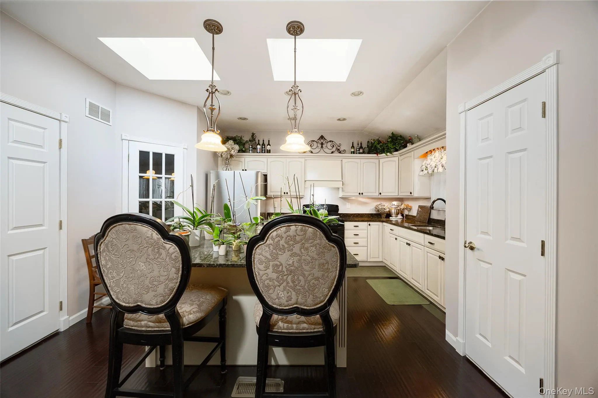 Kitchen featuring freestanding refrigerator, pendant lighting, white cabinetry, lofted ceiling, and dark wood-type flooring Kitchen featuring freestanding refrigerator, pendant lighting, white cabinetry, lofted ceiling, and dark wood-type flooring