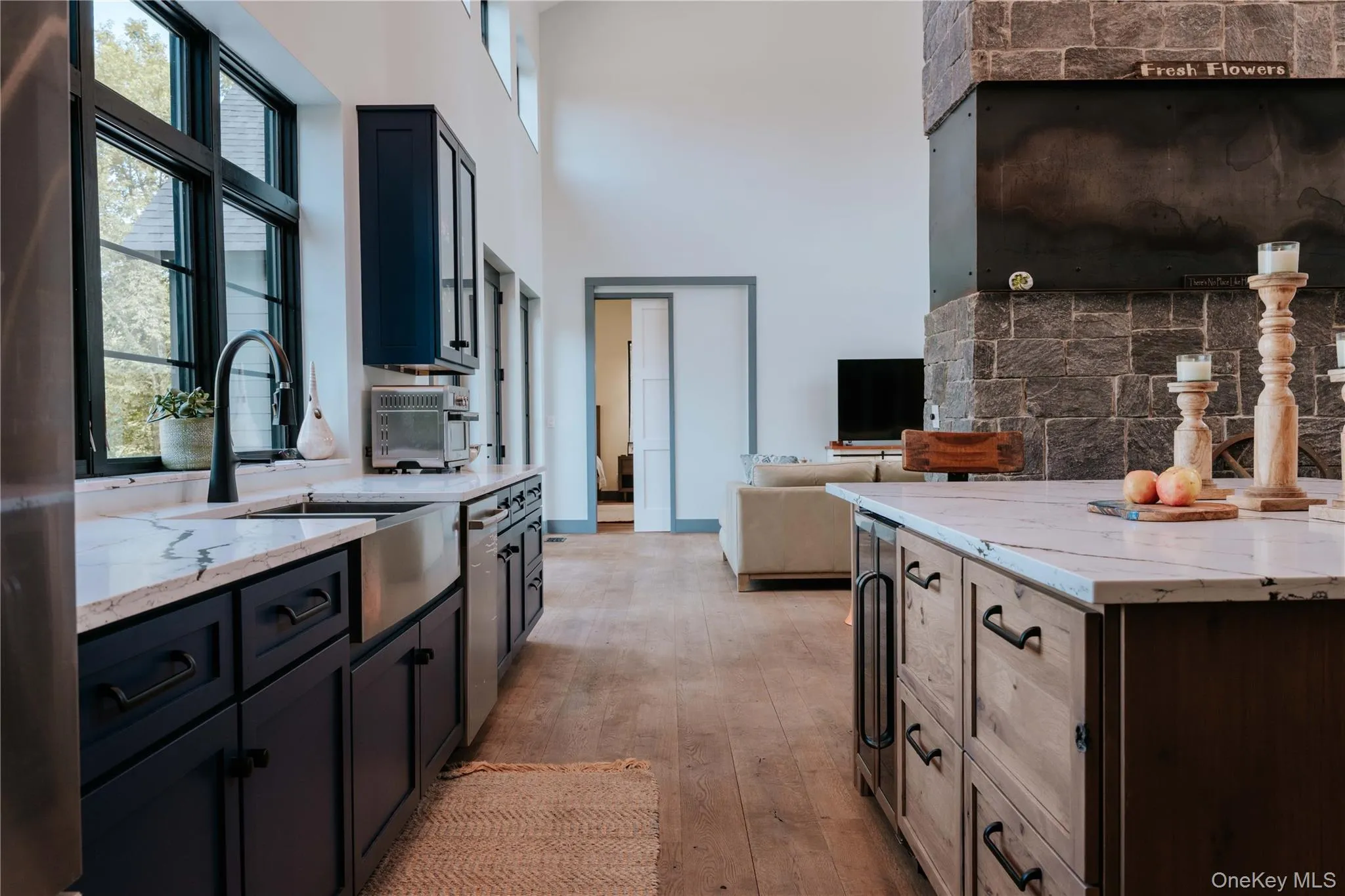Kitchen with light stone counters, light wood finished floors, open floor plan, wine cooler, and tasteful backsplash Kitchen with light stone counters, light wood finished floors, open floor plan, wine cooler, and tasteful backsplash