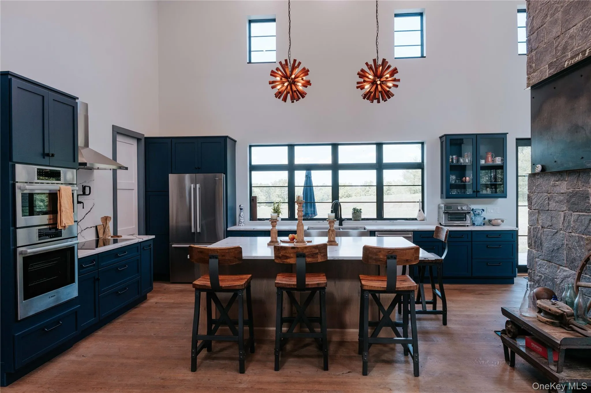 Kitchen with appliances with stainless steel finishes, light wood-style floors, light countertops, a kitchen breakfast bar, and blue cabinetry Kitchen with appliances with stainless steel finishes, light wood-style floors, light countertops, a kitchen breakfast bar, and blue cabinetry